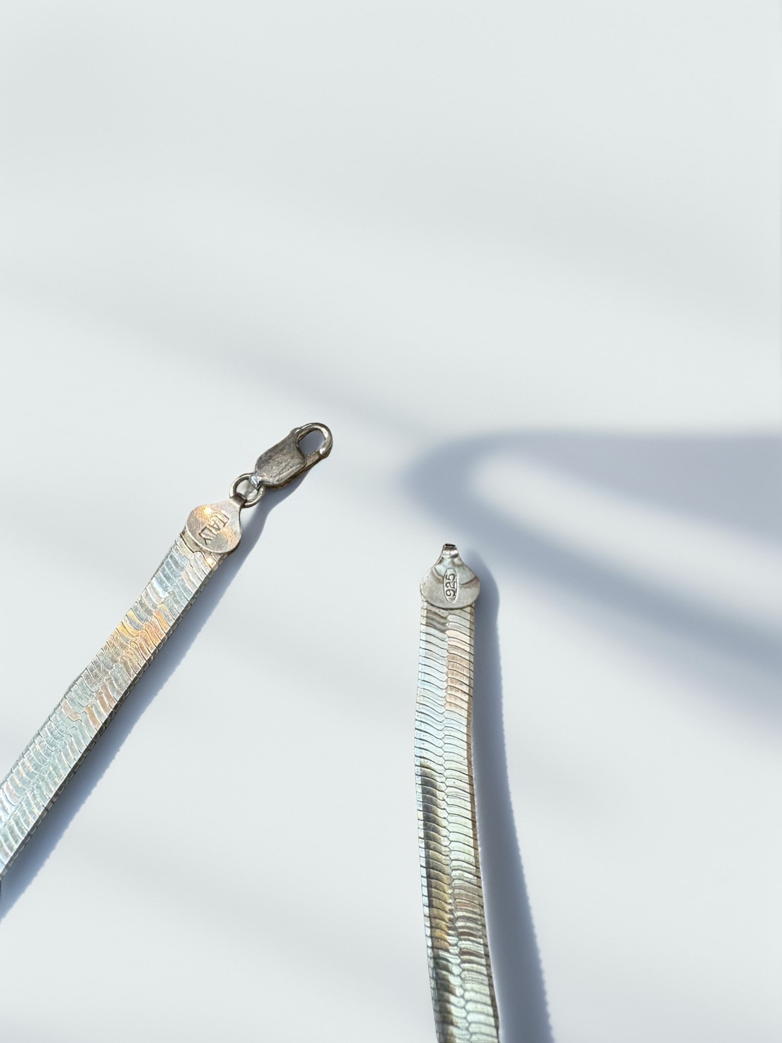 Italian Sterling Silver Herringbone Chain Necklace: This elegant herringbone chain necklace is crafted from high-quality .925 sterling silver, featuring a smooth, flat design that lies perfectly against the neck. Stamped 'ITALY' and '925', the piece re