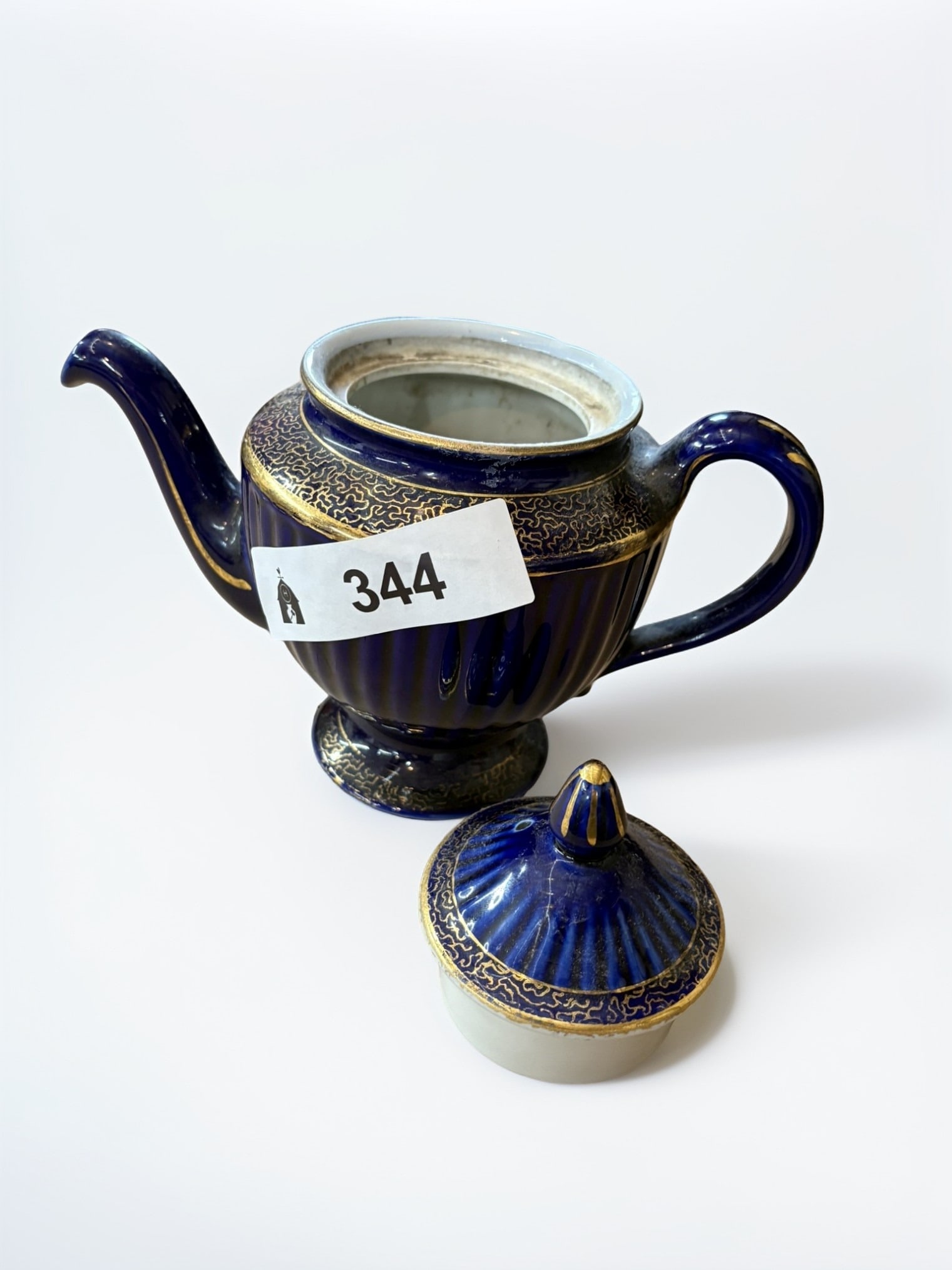 Cobalt Blue and Gold Gilt Fluted Porcelain Teapot: This elegant porcelain teapot features a striking deep cobalt blue glaze accented with intricate gold gilt scrollwork patterns around the shoulder and lid. The body is characterized by refined vertica