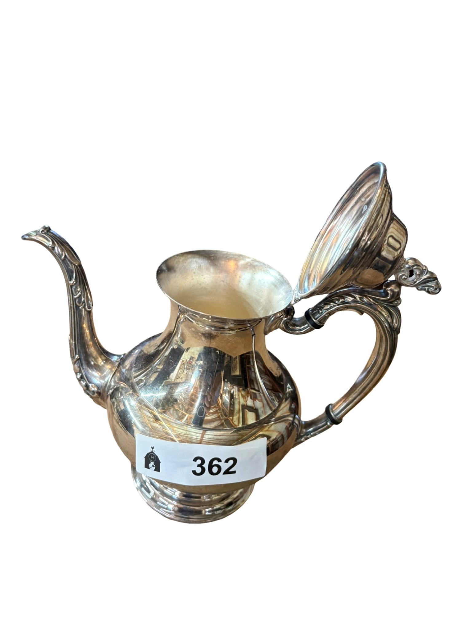 American Silver Plated Teapot with Ornate Spout and Handle: This elegant silver-plated teapot features a classic silhouette with a gracefully curved, ornately decorated spout and a matching scrolling handle. The piece is topped with a finely detailed finial an
