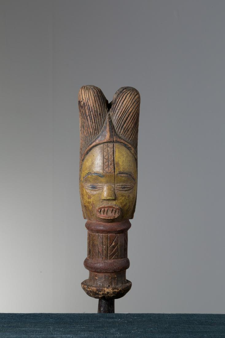 Wooden Kuyu sculpture depictig "Puppet head".: Scultura in legno e smalti raff. ''TESTA DI BURATTINO''. Etnia Kuyu. Repubblica Democratica del Congo. XX secolo. Patina e segni d'uso. Mis. Lung. cm. 8 Alt. cm. 30 Prof. cm. 6.5 ca.