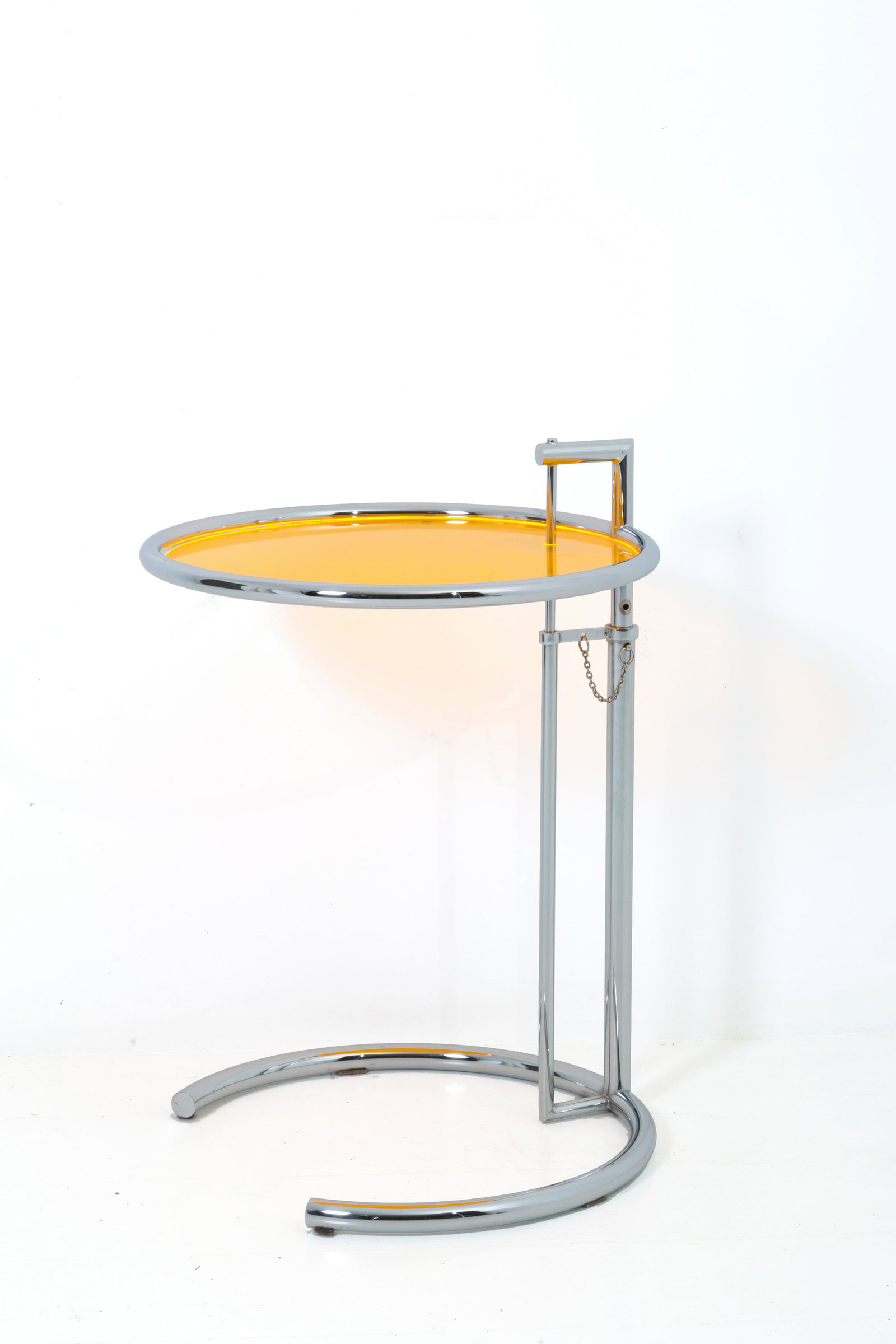 Steel coffee table with yellow plastic top. 1980s: Tavolino rotondo in acciaio cromato con piano in plastica gialla. Altezza regolabile. Anni '80. Mis. Alt. min. cm. 63 ca. e max cm. 99 ca. Mis. Alt. cm. 63 Diam. cm. 51 ca. Val. 200/300