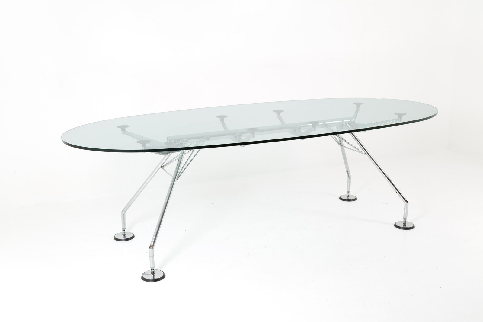NORMAN FOSTER for TECNO. Metal table Normos model: NORMAN FOSTER (Stockport, 1935) per TECNO. Tavolo modello Nomos in metallo cromato con piano ovale in cristallo molato. Marchio del produttore. Anni '70. Mis. Lung. cm. 241 Alt. cm. 72.5 Prof. cm. 110