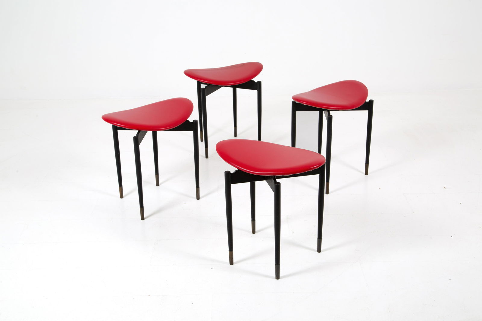 CARLO MOLLINO. Four stools with iron structure: CARLO MOLLINO (Torino, 1905-1973). Quattro sgabelli con struttura in ferro, puntali in ottone e seduta in vinile rosso. Anni '50. Mis. Lung. cm. 42 Alt. cm. 43 Prof. cm. 30 ca.