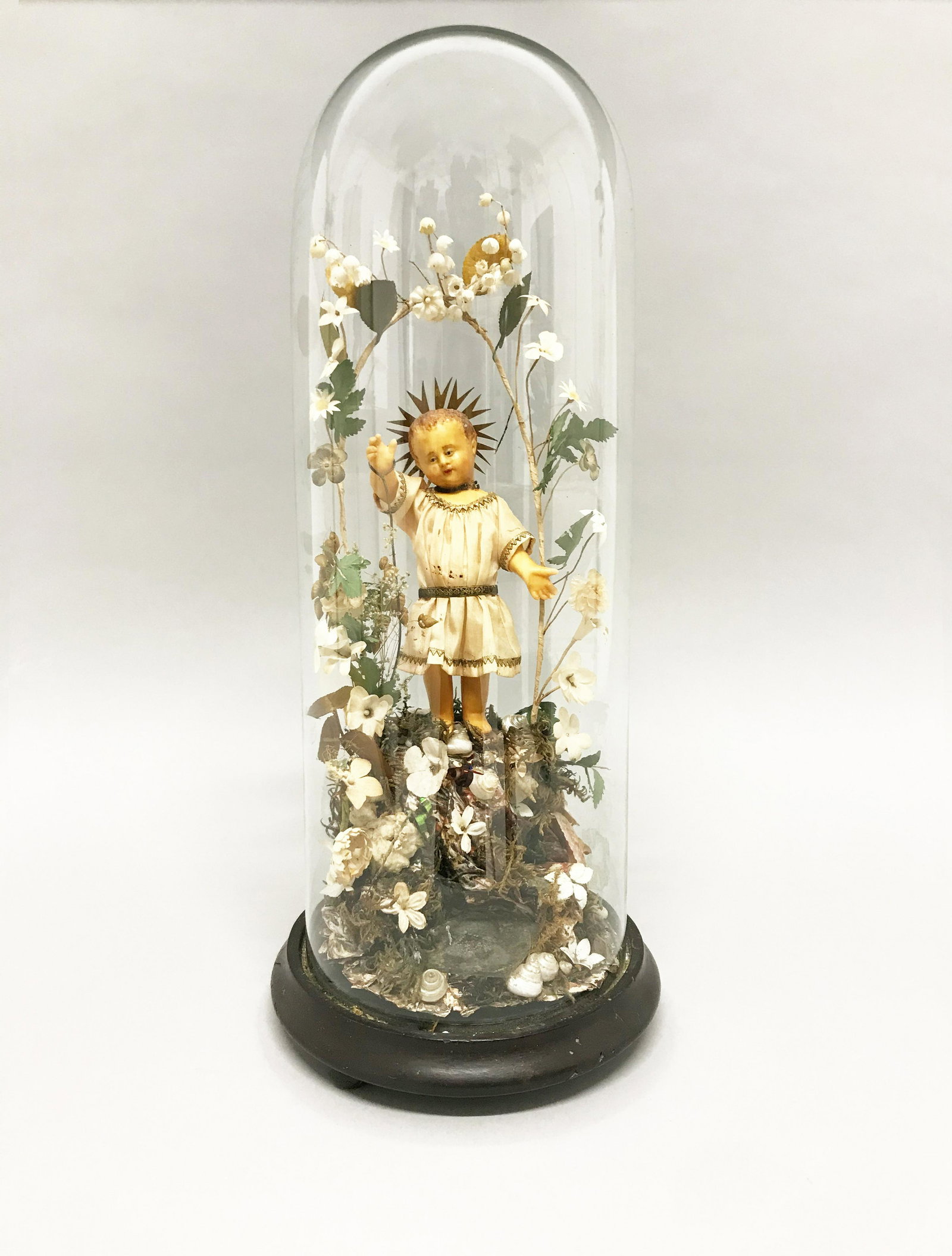 Wax Christ Child sculpture under glass bell: Scultura in cera raff. ''BAMBIN GESU' '' con fiori e piante. XX secolo. Sotto campana di vetro. Mis. Alt. cm. 50 ca. Val. 150/300