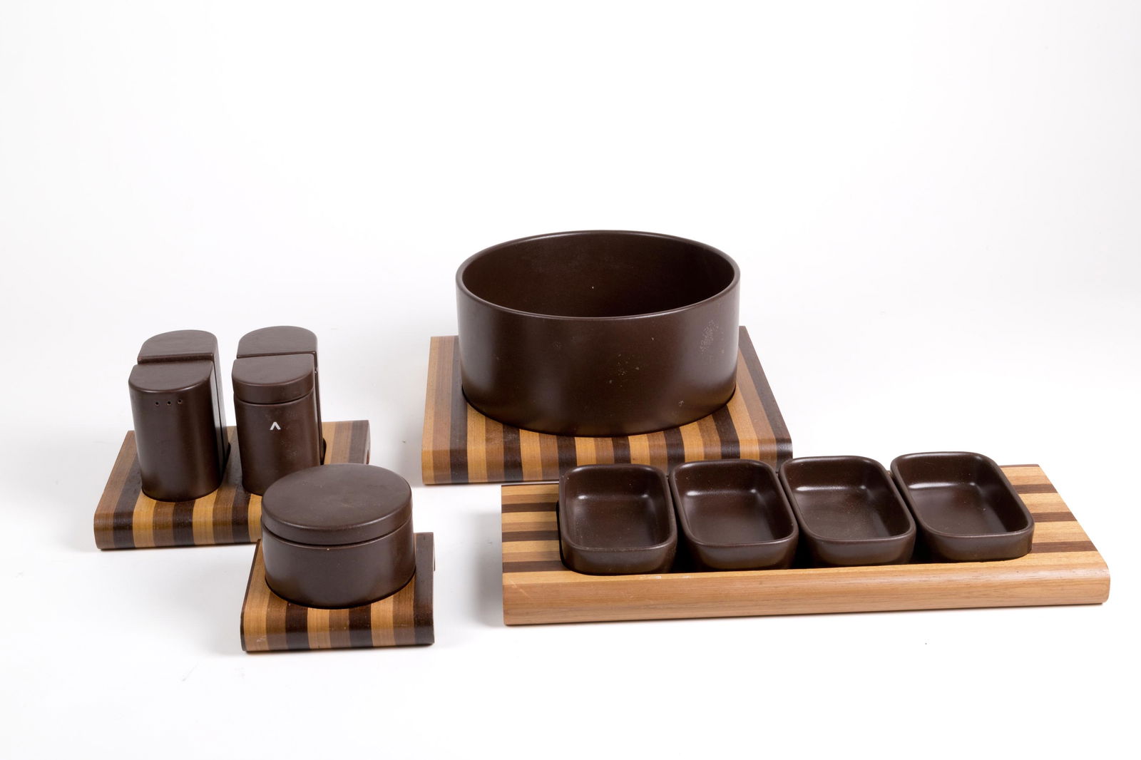 CERAMICHE FRANCO POZZI. Brown ceramic table-set: Set da tavola in ceramica marrone composto da antipastiera, insalatiera e un set per olio, aceto, sale e pepe. Supporti in legni vari stratificati. Produzione CERAMICHE FRANCO POZZI. Anni '80. Val. 50