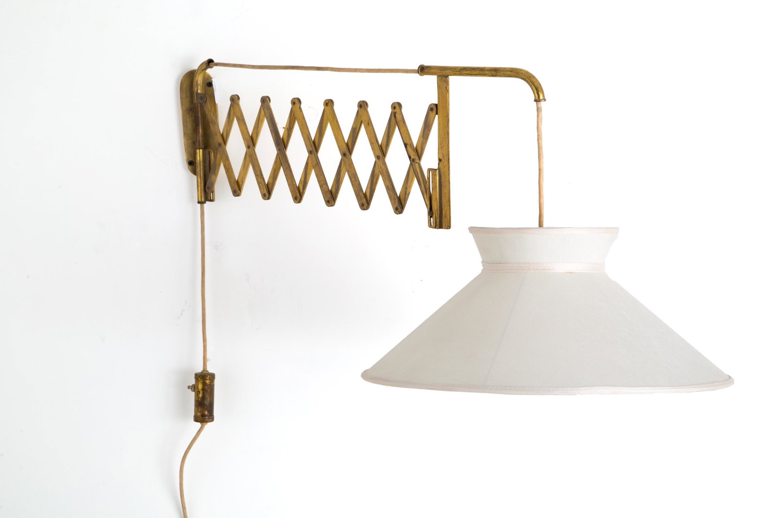 Brass and fabric wall lamp. Italy. 1950s: Lampada a muro con braccio estensibile in ottone con paralume in tessuto. Manifattura italiana. Anni '50. Misure da chiusa Lung. cm. 35 ca., da aperta Lung. cm. 96 ca. Vla. 300/400
