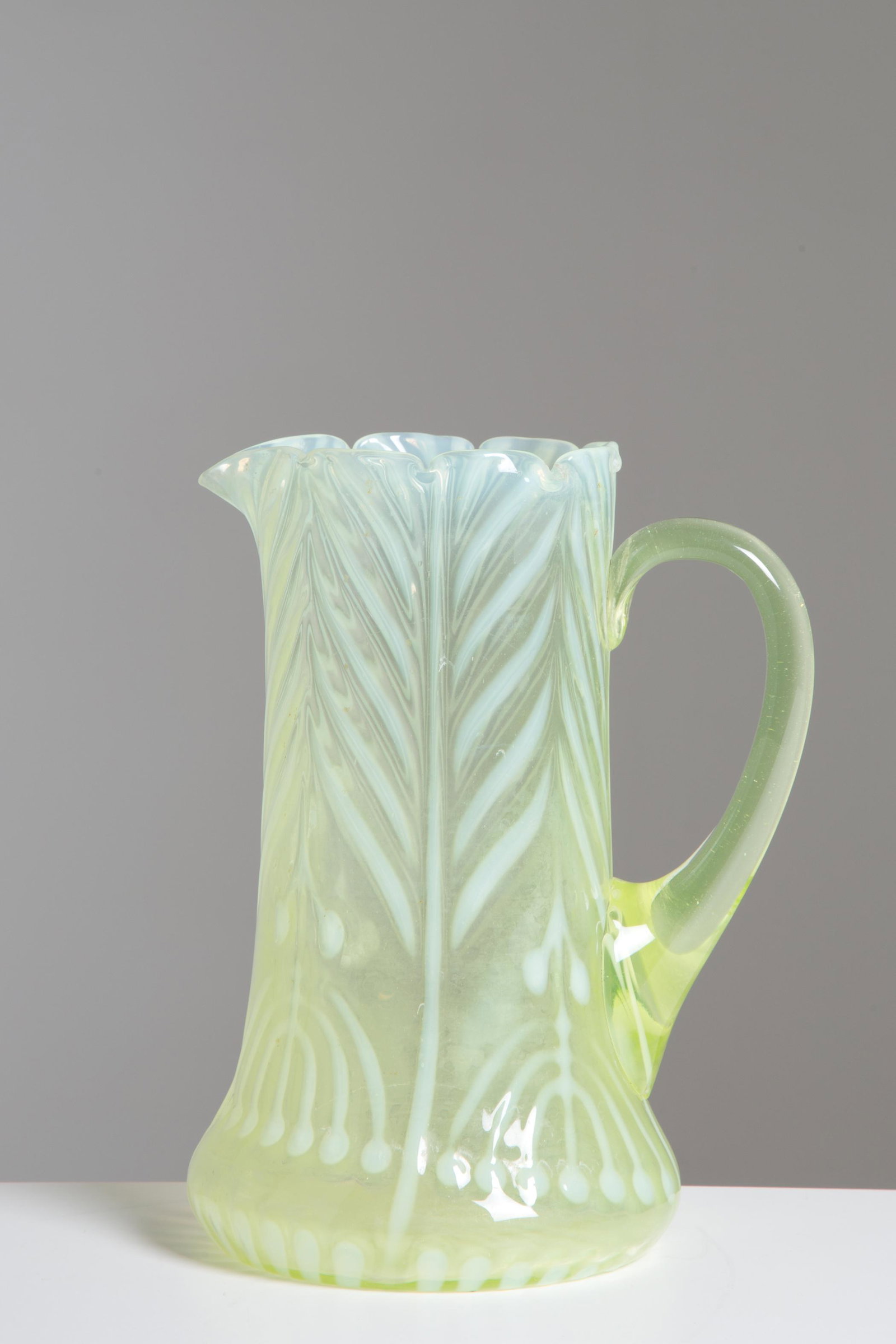 Decorated jug in vaseline glass. Early 20th c: Brocca in vetro all'uranio con decorazioni raffiguranti la Menorah. Inizi XX secolo. Mis. Alt. cm. 21 Diam. cm. 17 ca. Val. 300/400