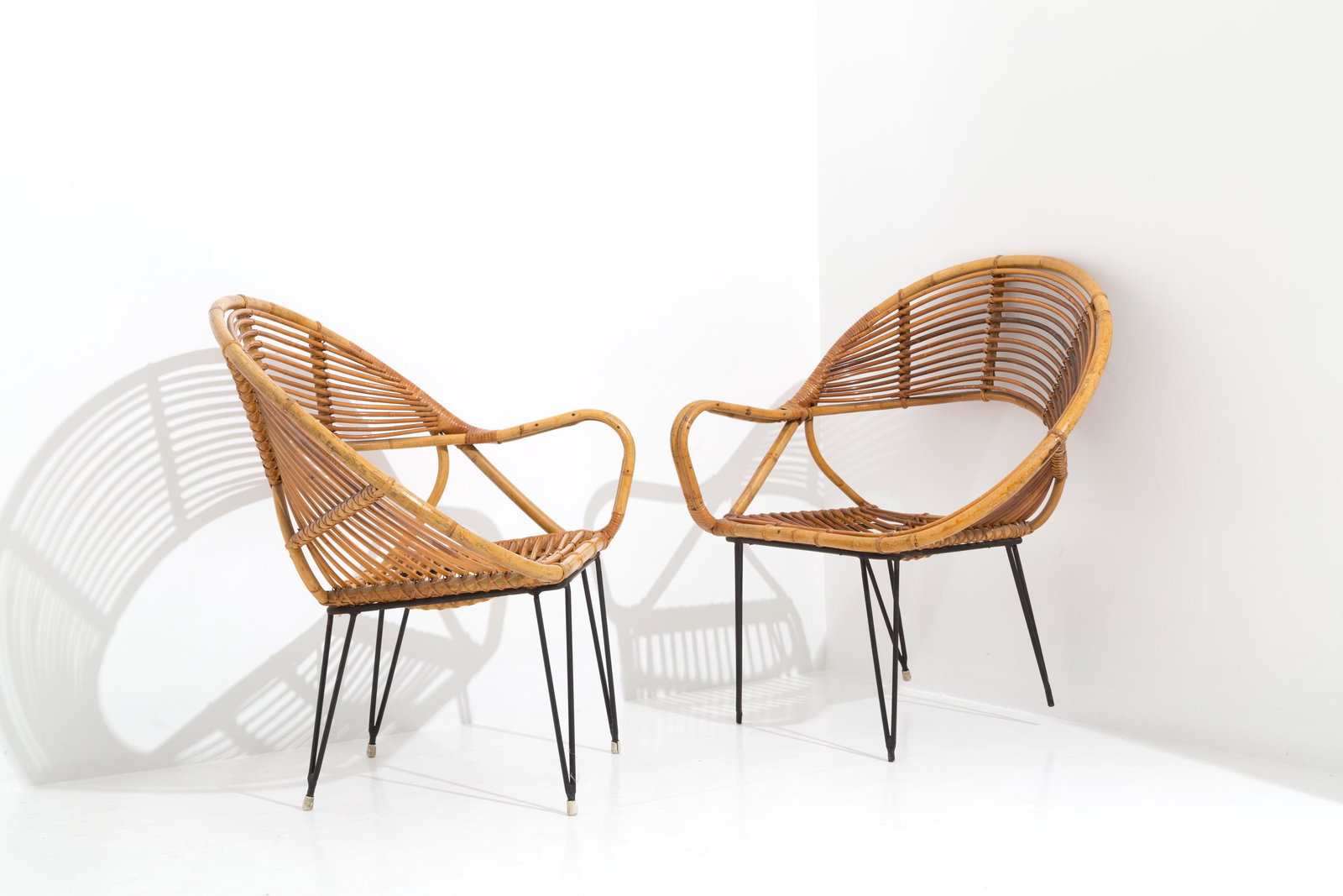 Pair of rattan armchairs with metal feet. '50s: Coppia di poltrone in rattan con piedi in metallo verniciato nero. Manifattura italiana. Anni '50. Lievi difetti. Mis. Lung. cm. 77 Alt. cm. 84 Prof. cm. 59 ca. Val. 500/700