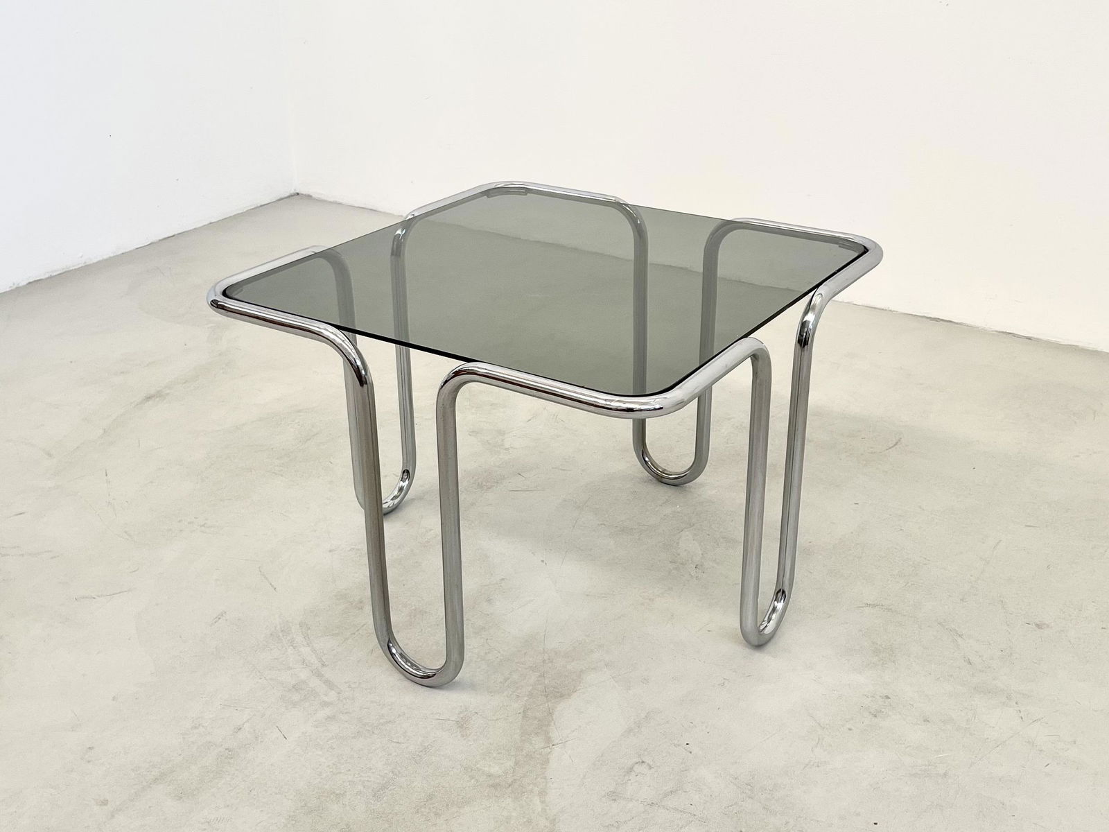 EZIO DIDONE. Brass and glass coffee-table. 1970s: EZIO DIDONE (Milano, 1939). Coffee-table in ottone cromato e vetro fumè. Anni '70. Mis. Lung. cm. 60 Alt. cm. 42 Prof. cm. 60 ca. Val. 300/600