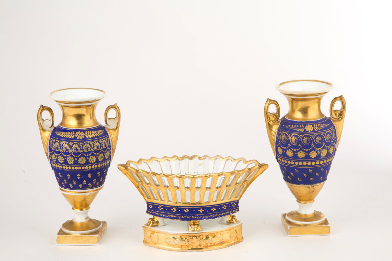 Porcelain triptych: Porcelain triptych decorated in gold and blue, consisting of two vases and a perforated basket. 19th century. Minor defects. Measurements of two jars: 22x13 cm approx. Basket dimensions: 12x21.5 cm ap
