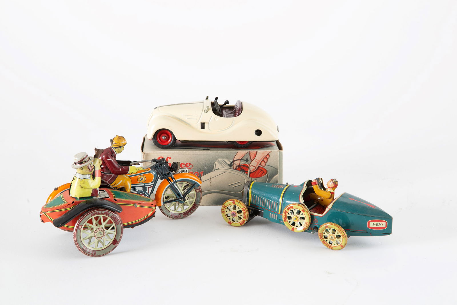 Three tin toys: Three enameled tin toys, two of which are cars and a sidecar. One car in its original box, manufactured by SCHUCO Examico 4001. Early 20th century. Tre giocattoli in latta smalata dei quali due autove