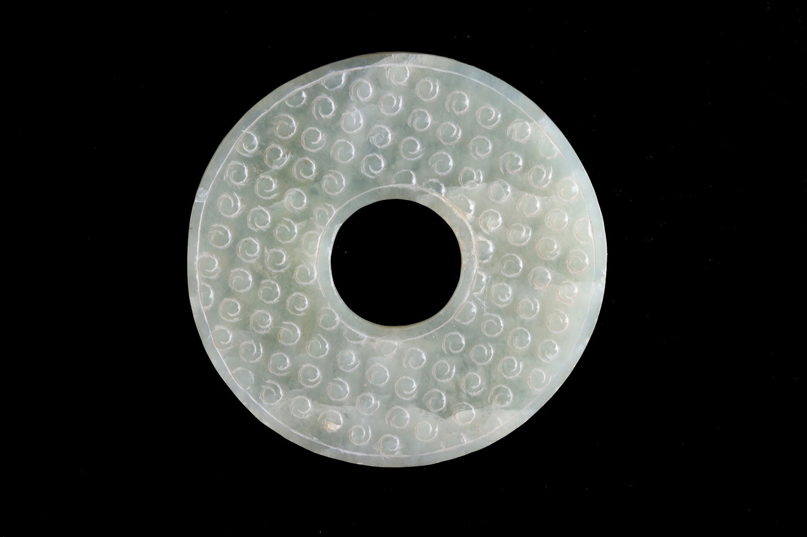Jade Bi Disc: Jade Bi Disc with a millet grain motif. China. Diam. 9 cm approx. Disco Bi in giada con motivo ?a chicco di miglio?. Cina. Diam. 9 cm ca.