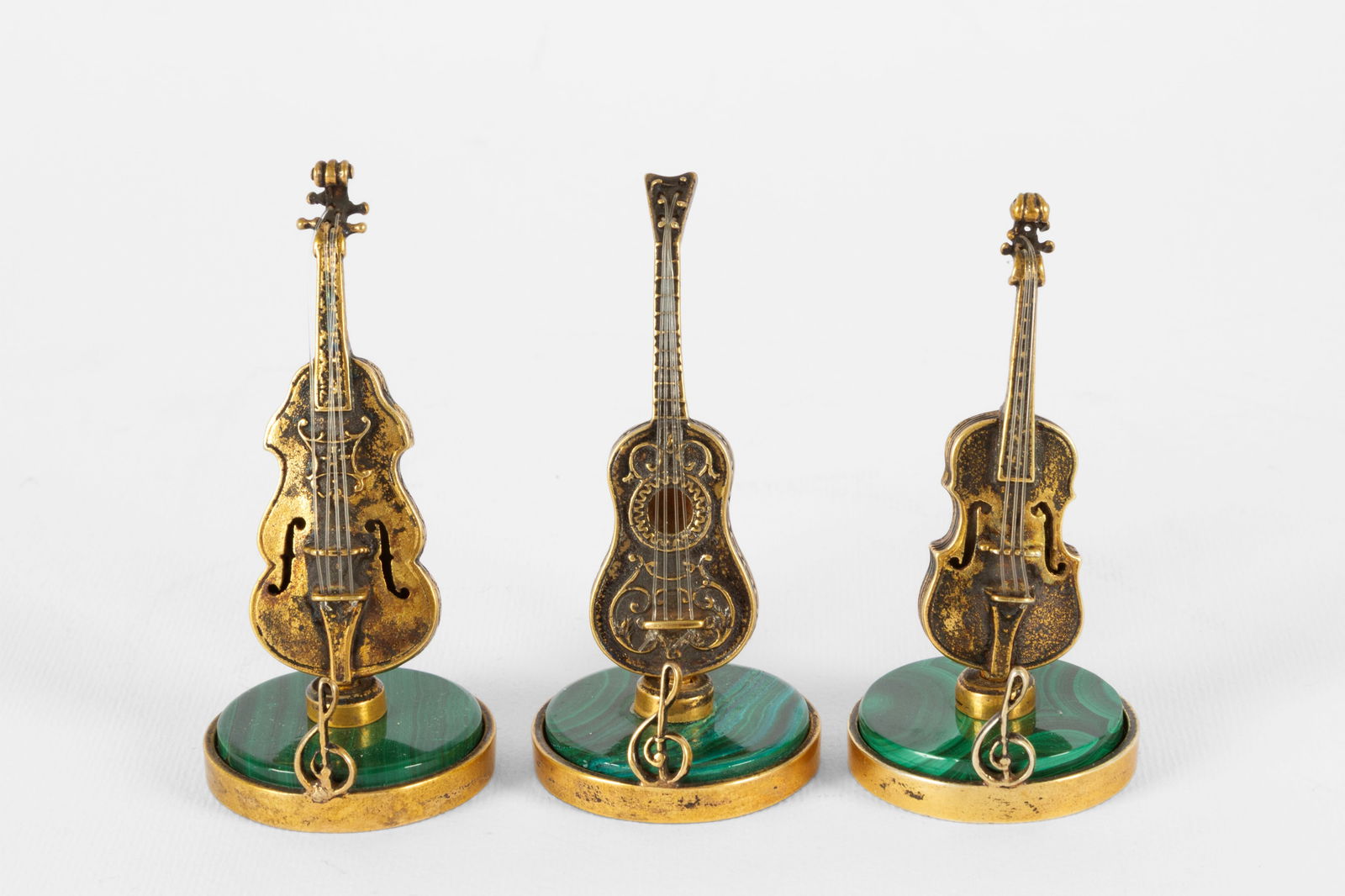 Three models of musical instruments in malachite and silver: Three models of musical instruments in malachite and finely chiseled and gilded silver. 20th century. Minor defects. Height approx. 6 cm. Tre modellini di strumenti musicali in malachite e argento