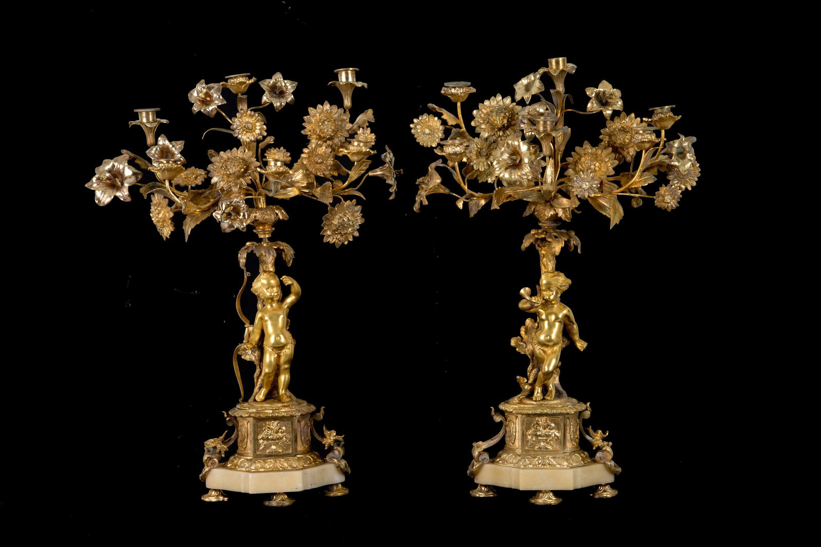 Pair of candlesticks: Pair of six-light gilded bronze and onyx candelabras with cherubs and flowers. 20th century. Defects, breaks, and missing parts. 64x47x17 cm approx. Coppia di candelabri a sei luci in bronzo dorato e
