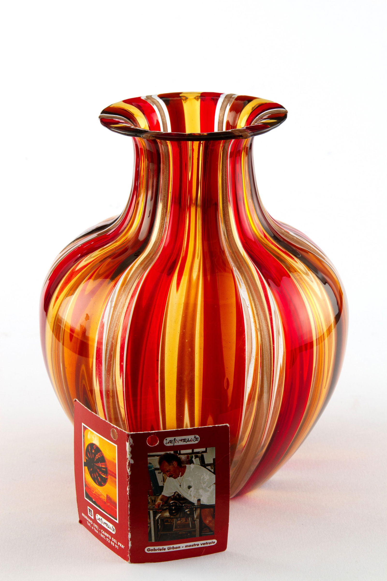 GABRIELE URBAN. Red striped vase: GABRIELE URBAN (Italia, XX secolo). Red, yellow, and ochre striped glass vase. With a certificate of guarantee. 20.5x17 cm approx. GABRIELE URBAN (Italia, XX secolo). Vaso in vetro striato rosso, gial