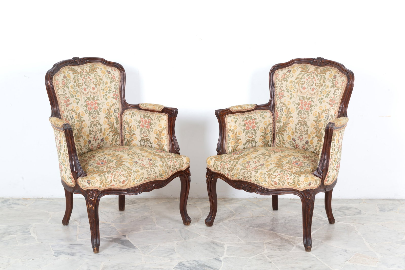 Due poltrone in legno tinto: Two carved and stained wooden armchairs with seats and backs upholstered in floral fabric. 19th century. Minor defects. 80x67x60 cm approx. Due poltrone in legno scolpito e tinto con seduta e schienal