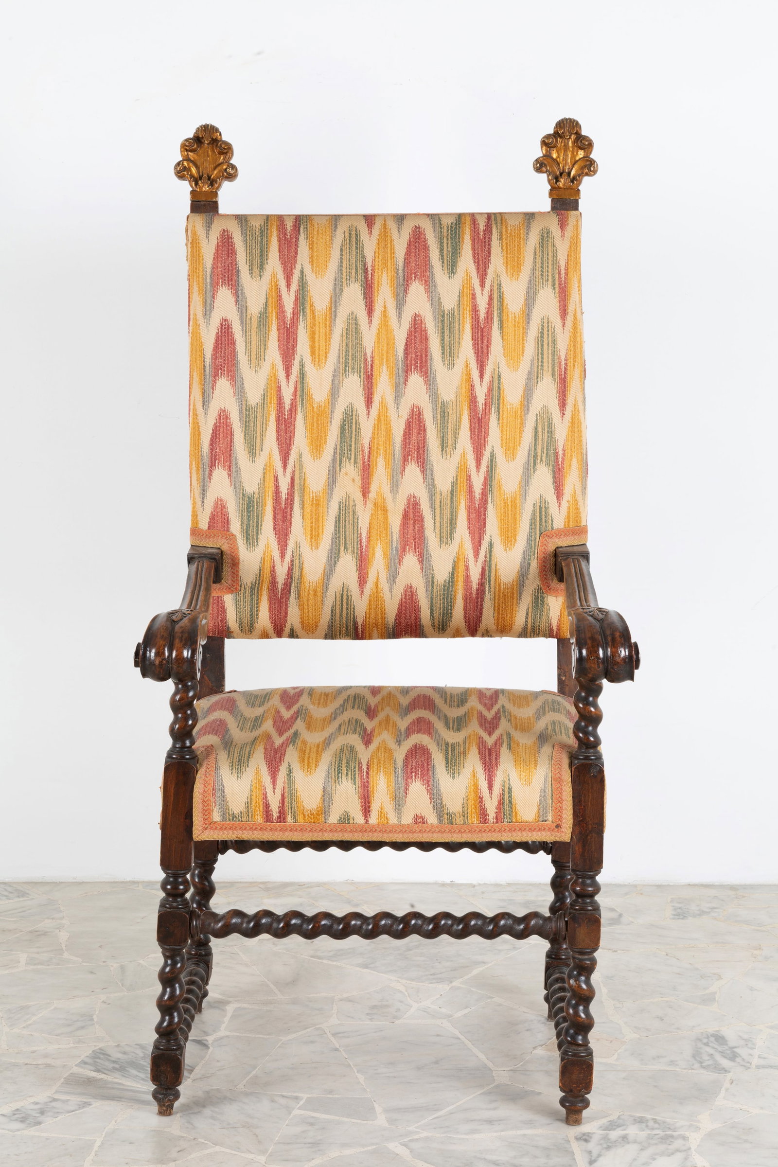 Poltrona in legno: Carved wooden armchair with turned legs joined by turned crosspieces and flamed cotton upholstery. 17th century with restorations. Defects. 154x73x64 cm approx. Poltrona in legno intagliato con gambe 