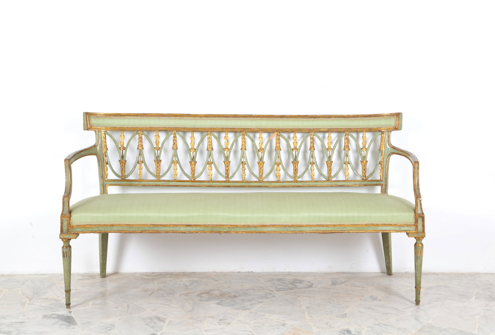 Divanetto laccato verde: Green and gilt lacquered wooden sofa with perforated panels. Directoire period. Minor defects and restorations. 89x173x52 cm approx. Divanetto in legno laccato verde e dorato con cartelle traforate.