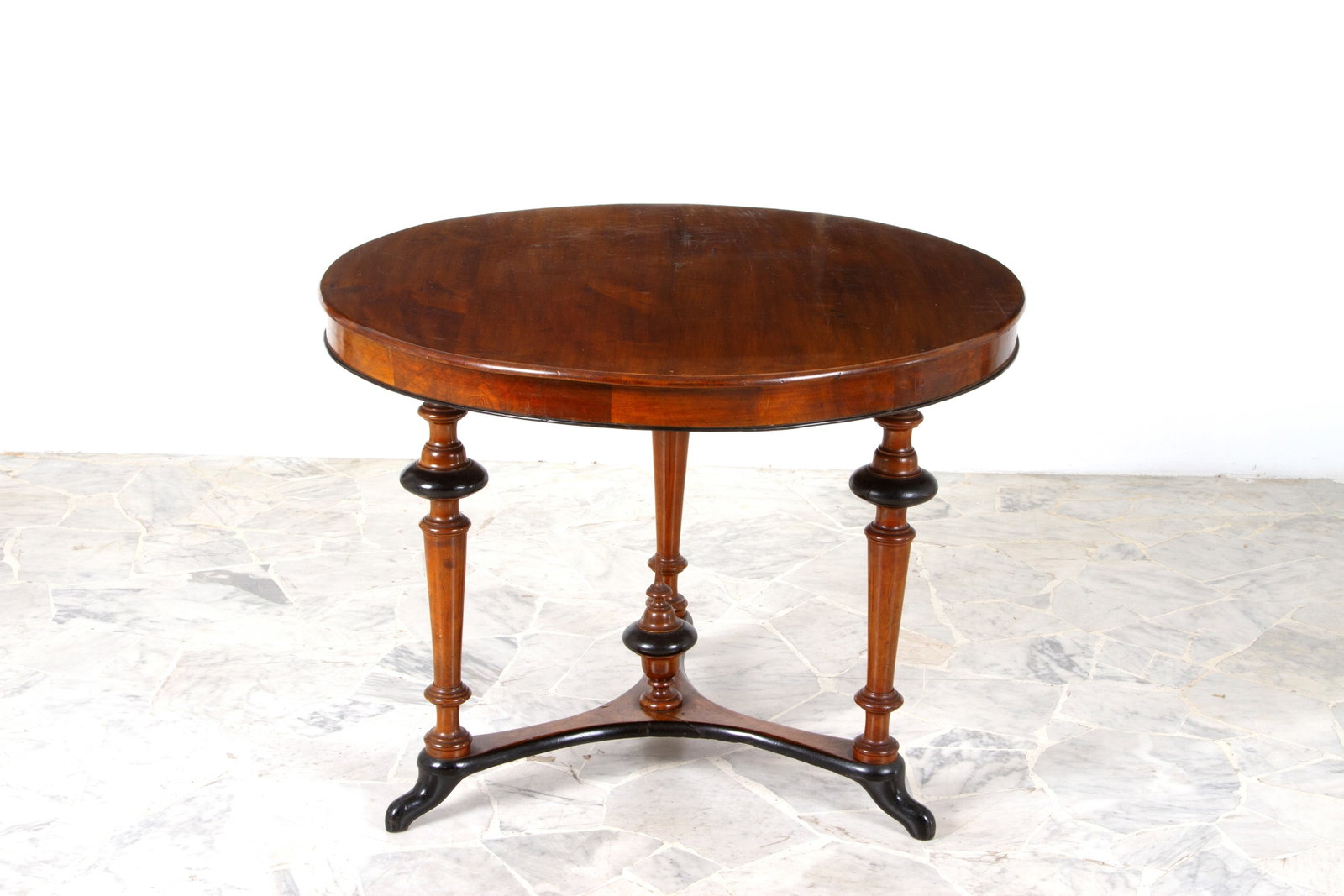 Coffee table with legs joined by crosspieces: Round table in walnut veneer and ebonized wood. Three legs joined by a crosspiece with a central finial. 19th century. 69x90 cm approx. Tavolino rotondo lastronato in noce e legno ebanizzato. Tre gamb