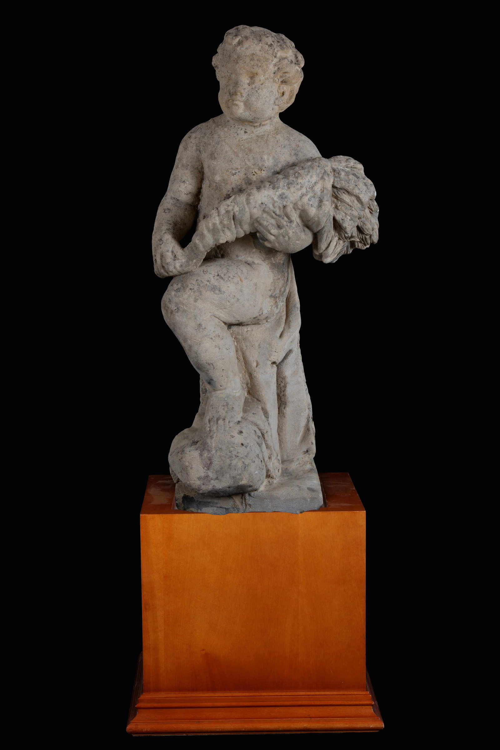 Scultura "PUTTO CON CORNUCOPIA": Stone sculpture depicting "PUTTO WITH CORNUCOPIA". Wooden base. Second half of the 18th century.Measures of the base: 45x52x52 cm approx. Height approx. 115 cm. Scultura in pietra raffigurante "PUTTO