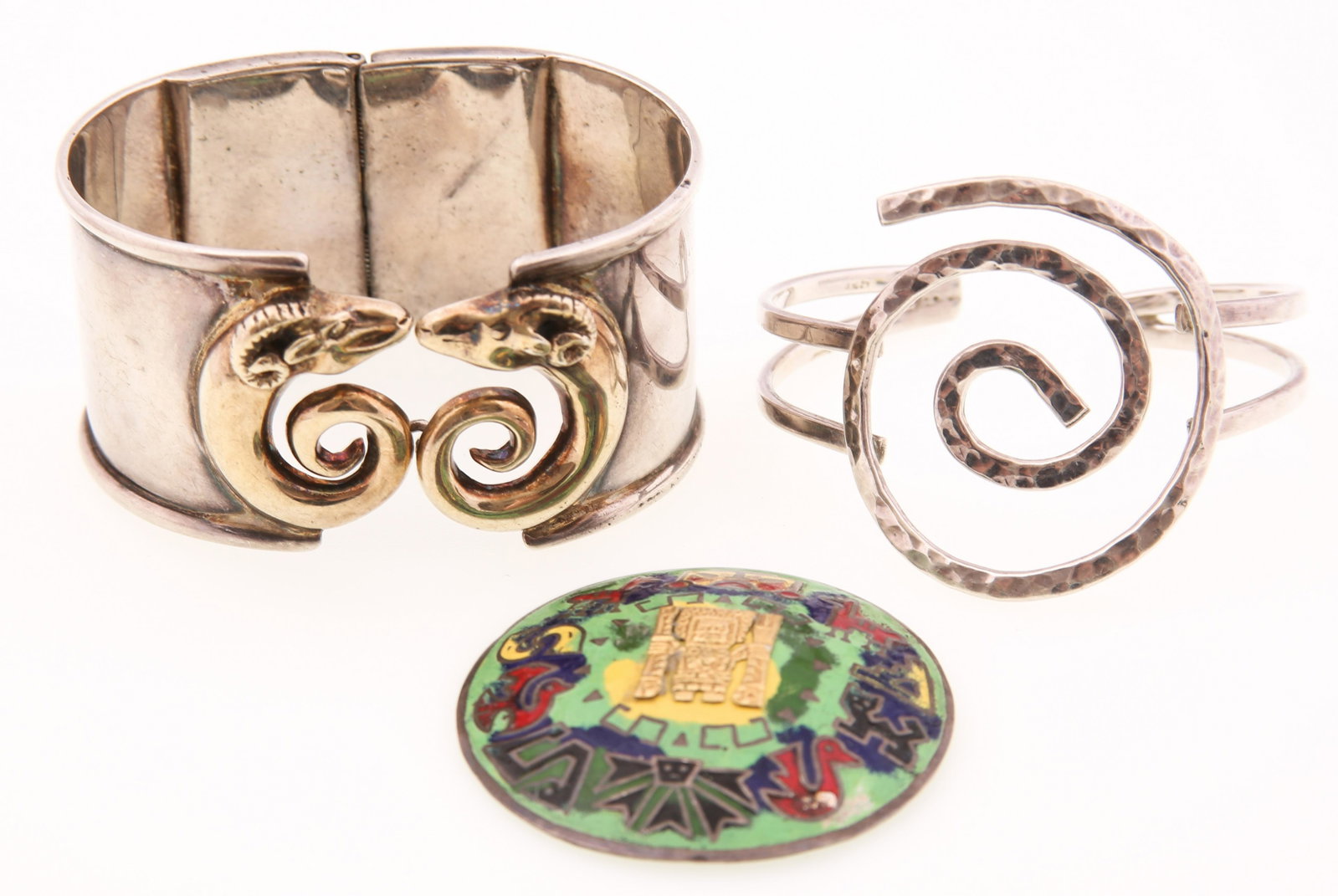 STERLING SILVER BRACELETS & BROOCH - LOT OF 3: STERLING SILVER BRACELETS & BROOCH - LOT OF 3 Sterling silver bracelets and brooch, includes: Hammer finish, swirl design cuff Ram design hinge cuff Enamel and 18K yellow gold accented Mayan them