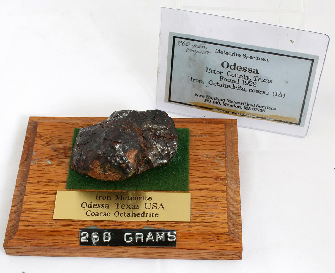 1922 ODESSA METEORITE 260.5 GRAMS WITH WOODEN STAND: 1922 ODESSA METEORITE 260.5 GRAMS WITH WOODEN STAND Iron meteorite found in Odessa, Texas in 1922. Includes identification card from the New England Meteoritical Services and wooden stand with plaque.