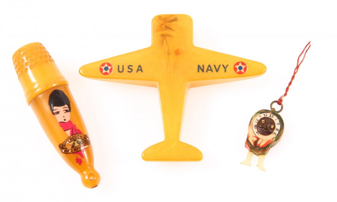 BAKELITE SEWING SOUVENIR, CHARM, SHARPENER - LOT OF 3: BAKELITE SEWING SOUVENIR, CHARM, SHARPENER - LOT OF 3 Lot of three early 20th century Bakelite items, to include US Navy plane pencil sharpener, souvenir sewing container, and google eye clock charm. 
