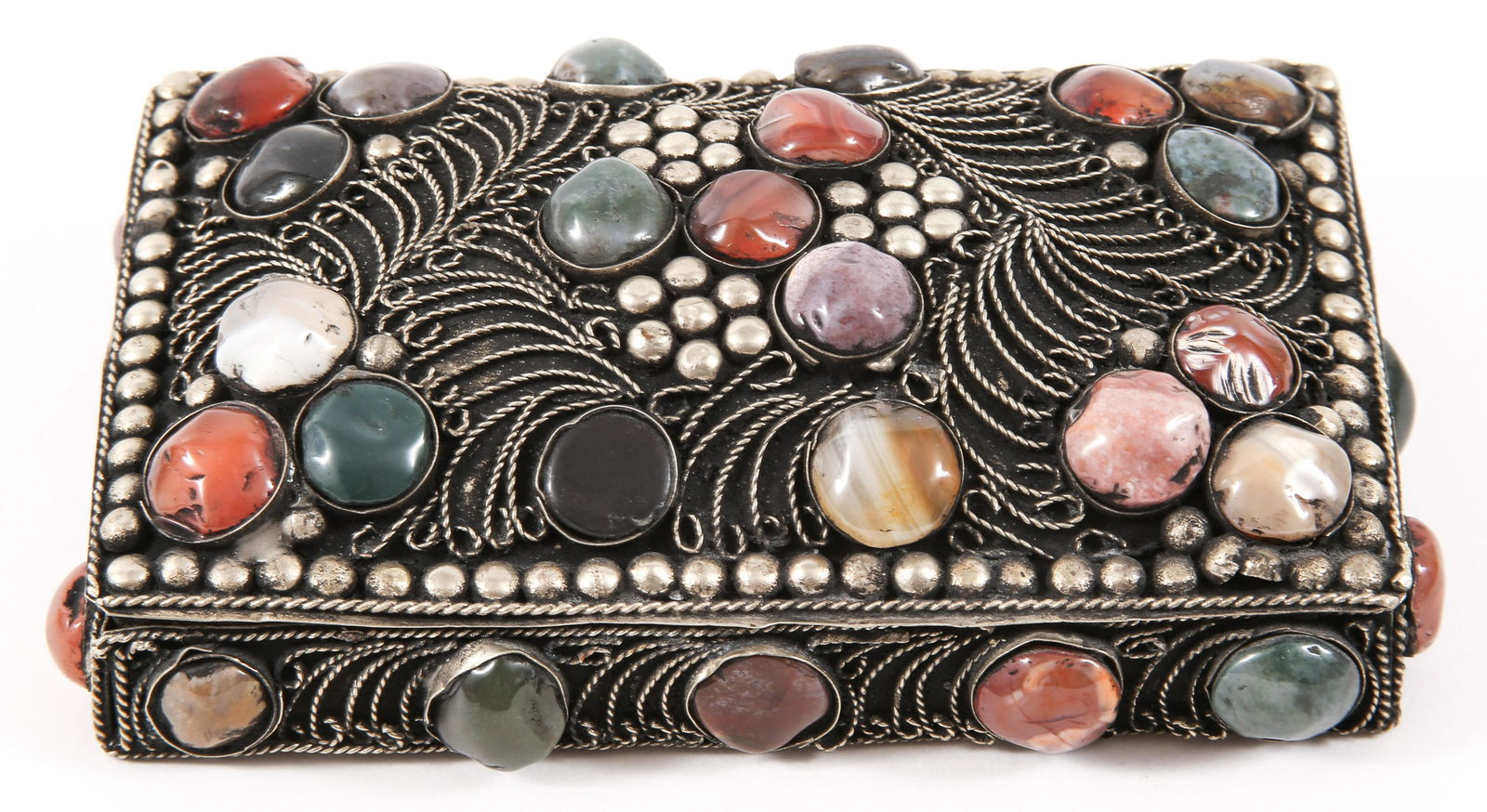 INDIAN WHITE METAL FILIGREE AGATE STONE TRINKET BOX: INDIAN WHITE METAL FILIGREE AGATE STONE TRINKET BOX Indian white metal trinket box decorated with filigree and mixed agate stone cabochons. Size: 5.25 x 3.25 x 1.25"