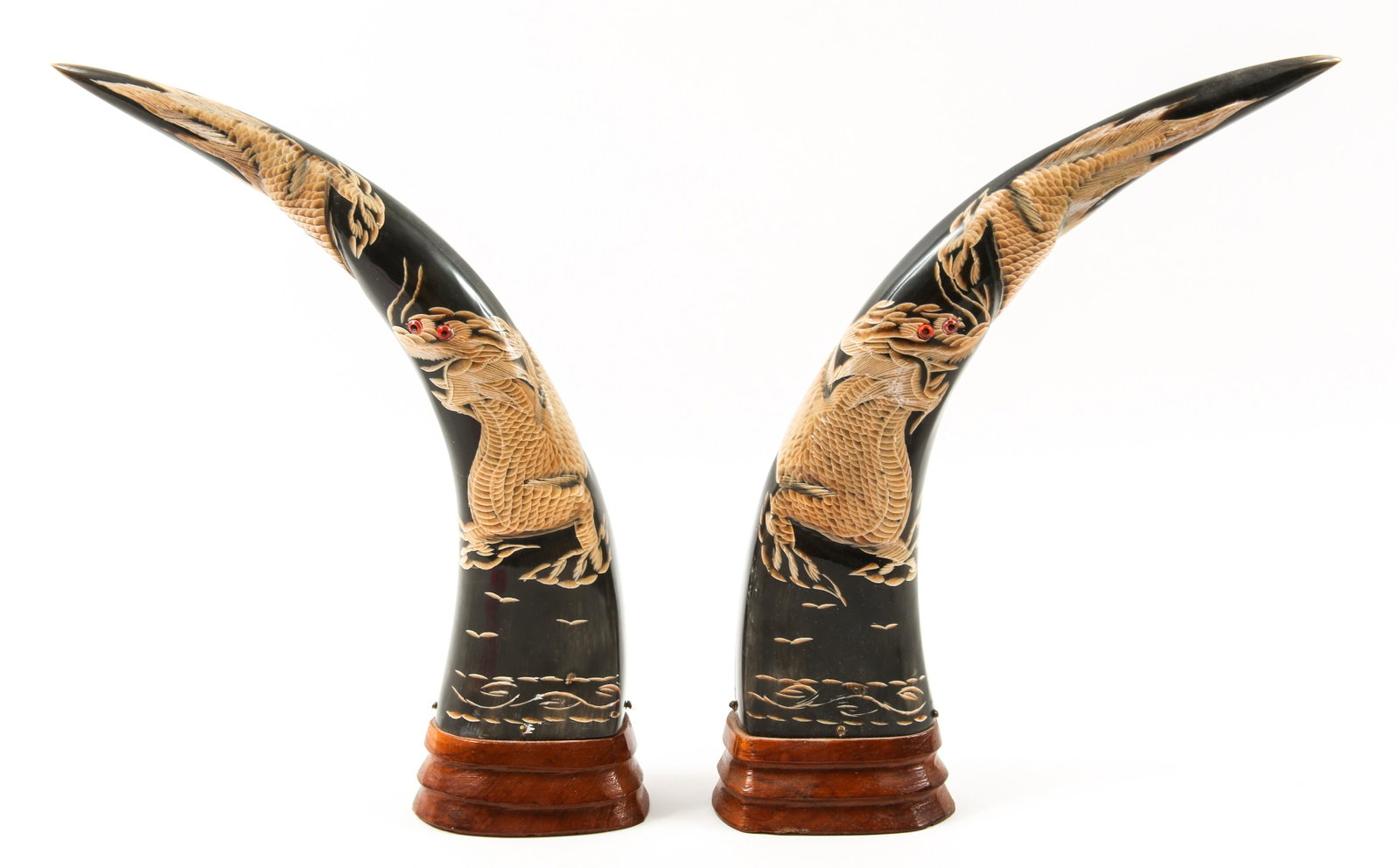 CHINESE CARVED WATER BUFFALO HORNS - DRAGONS: CHINESE CARVED WATER BUFFALO HORNS - DRAGONS Lot of two Chinese carved ox horns mounted on wood stands, depicting dragons with glass eye inlay. Size: 10"