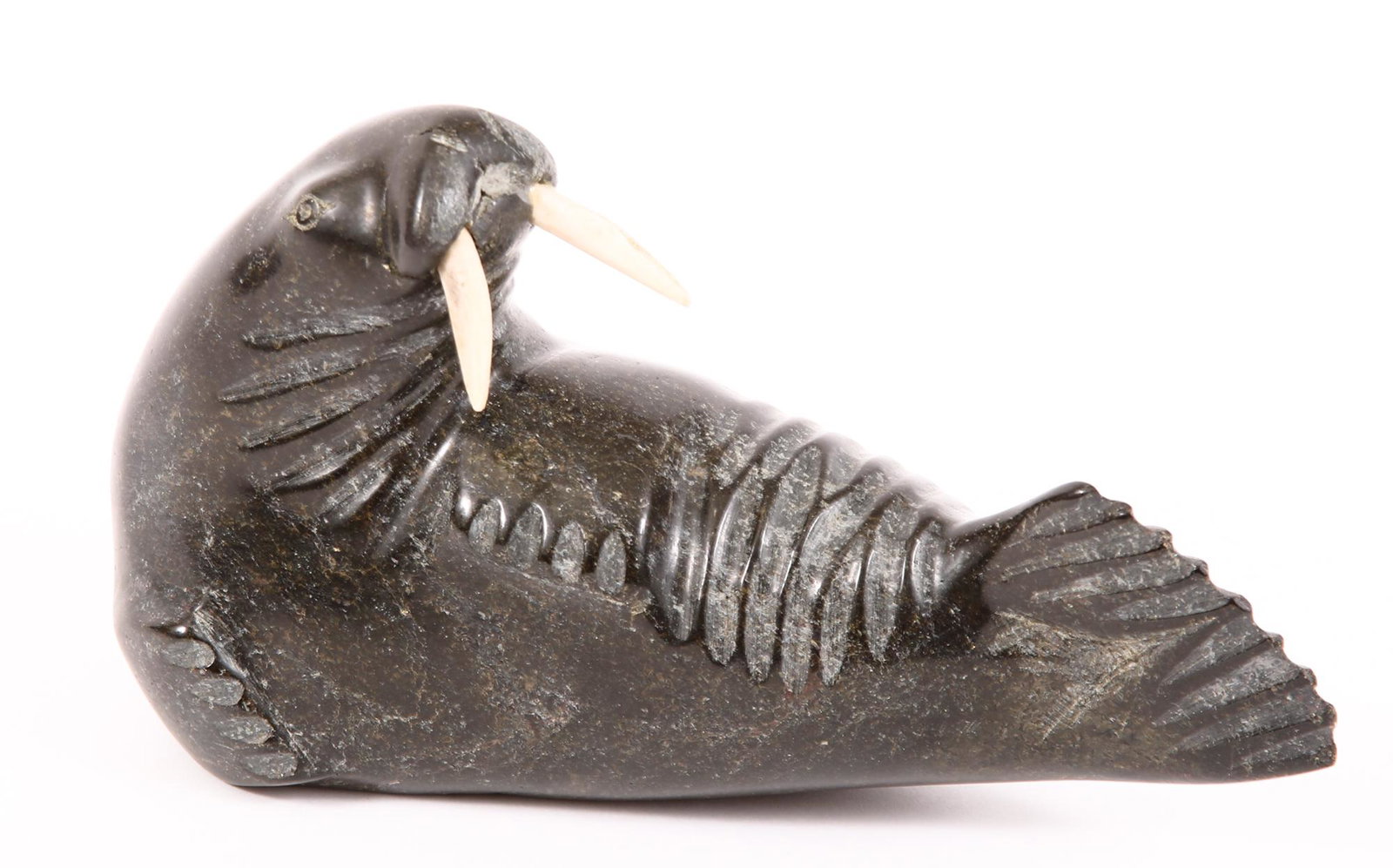 INUIT CARVED STONE WALRUS SCULPTURE - SIGNED: INUIT CARVED STONE WALRUS SCULPTURE - SIGNED Inuit carved stone sculpture of a walrus, with carved bone tusks, initialed on underside. Size: 8 x 4.5"