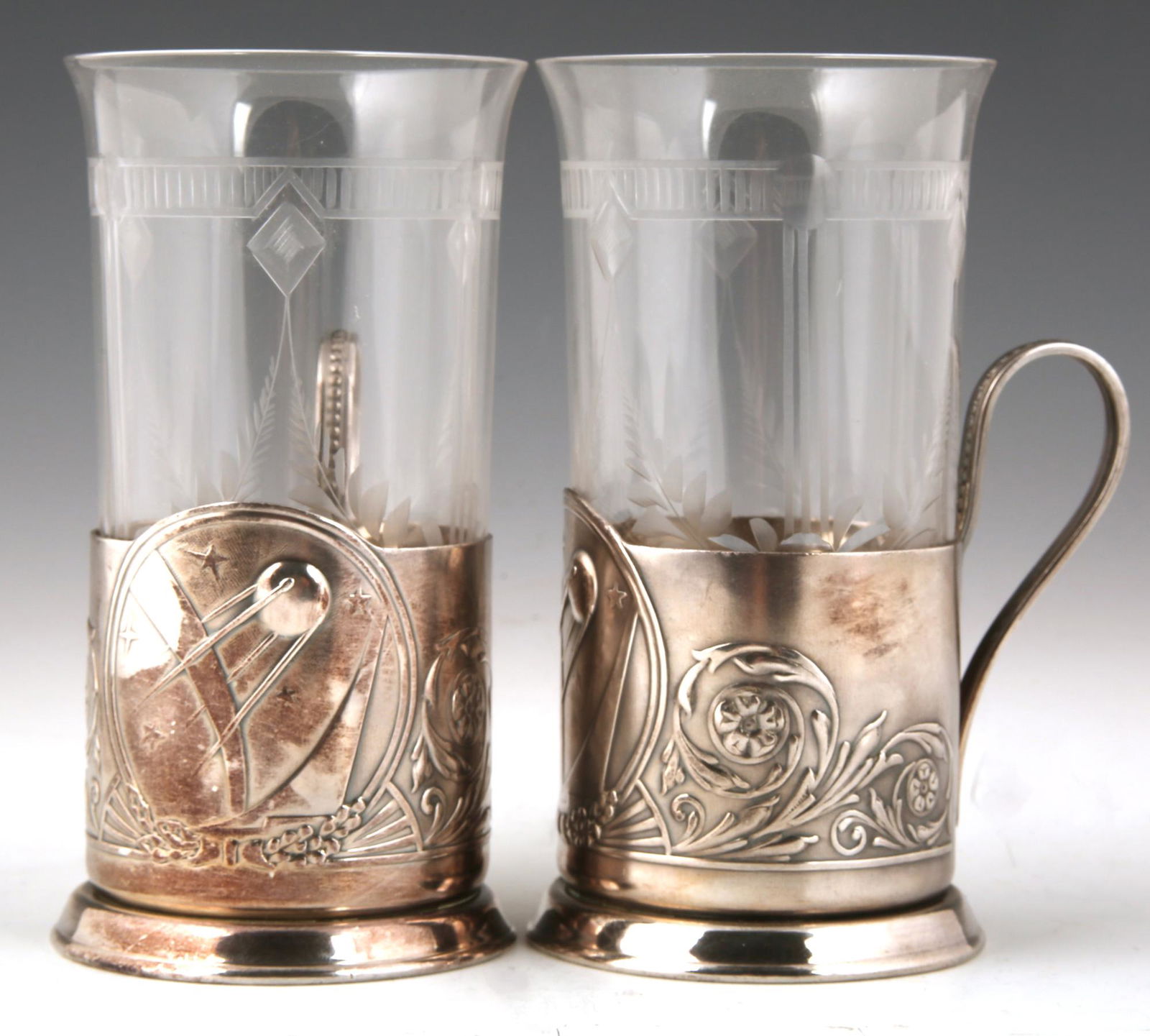 PAIR OF SOVIET SILVER PLATED SPUTNIK PODSTAKANNIK: PAIR OF SOVIET SILVER PLATED SPUTNIK PODSTAKANNIK Pair of silver plated Soviet era Russian Podstakannik tea glass holders with a Sputnik design. Tea glasses are not original to set. Measure 6" tall wi