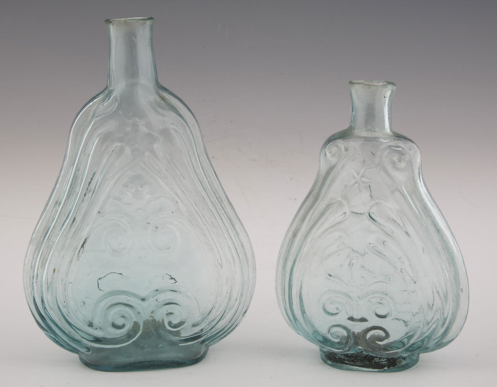 VIOLIN SCROLL AND STAR FLASKS - LOT OF 2: VIOLIN SCROLL AND STAR FLASKS - LOT OF 2 Lot of two light blue flasks in the shape of a violin scroll. Includes: Flask with scroll and star pattern, pontil scar and whittled neck. Measures 5 x 2 x 7.