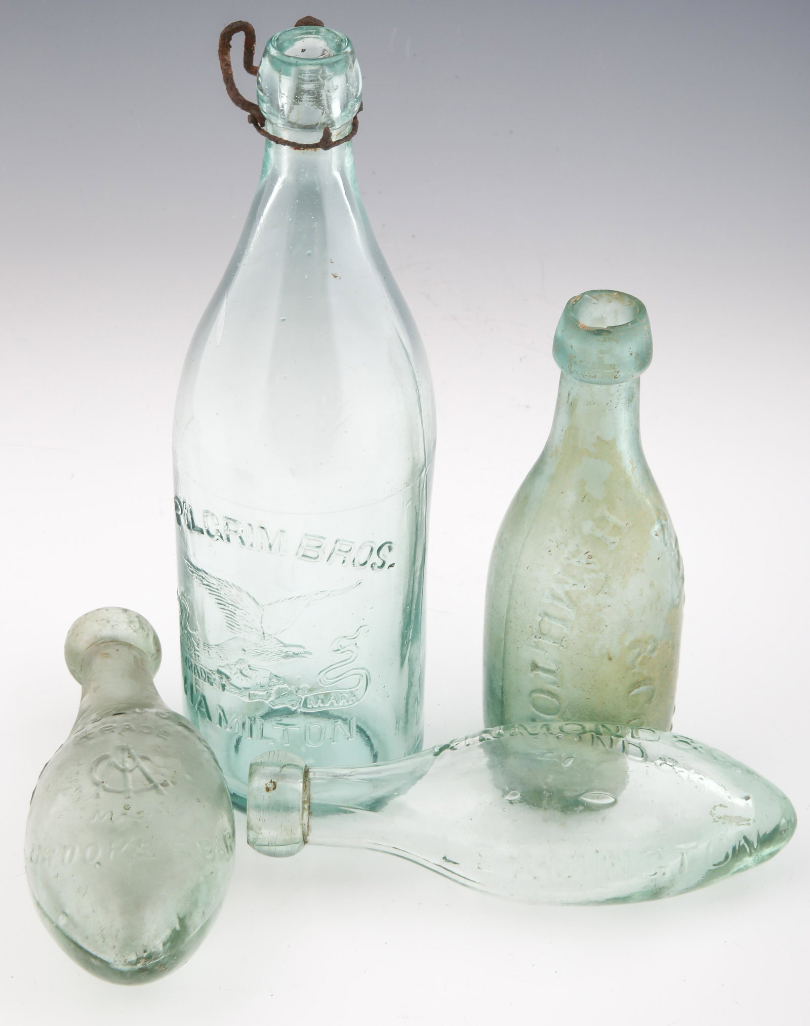 19TH C. GLASS BOTTLES & TORPEDO BOTTLES - LOT OF 4: 19TH C. GLASS BOTTLES & TORPEDO BOTTLES - LOT OF 4 Lot of four 19th century glass bottles. Includes: R.A. Pilgrim & Co. bottle. Marked "R.A. Pilgrim & Co. Hamilton C. W." Measures 7.25" tall a