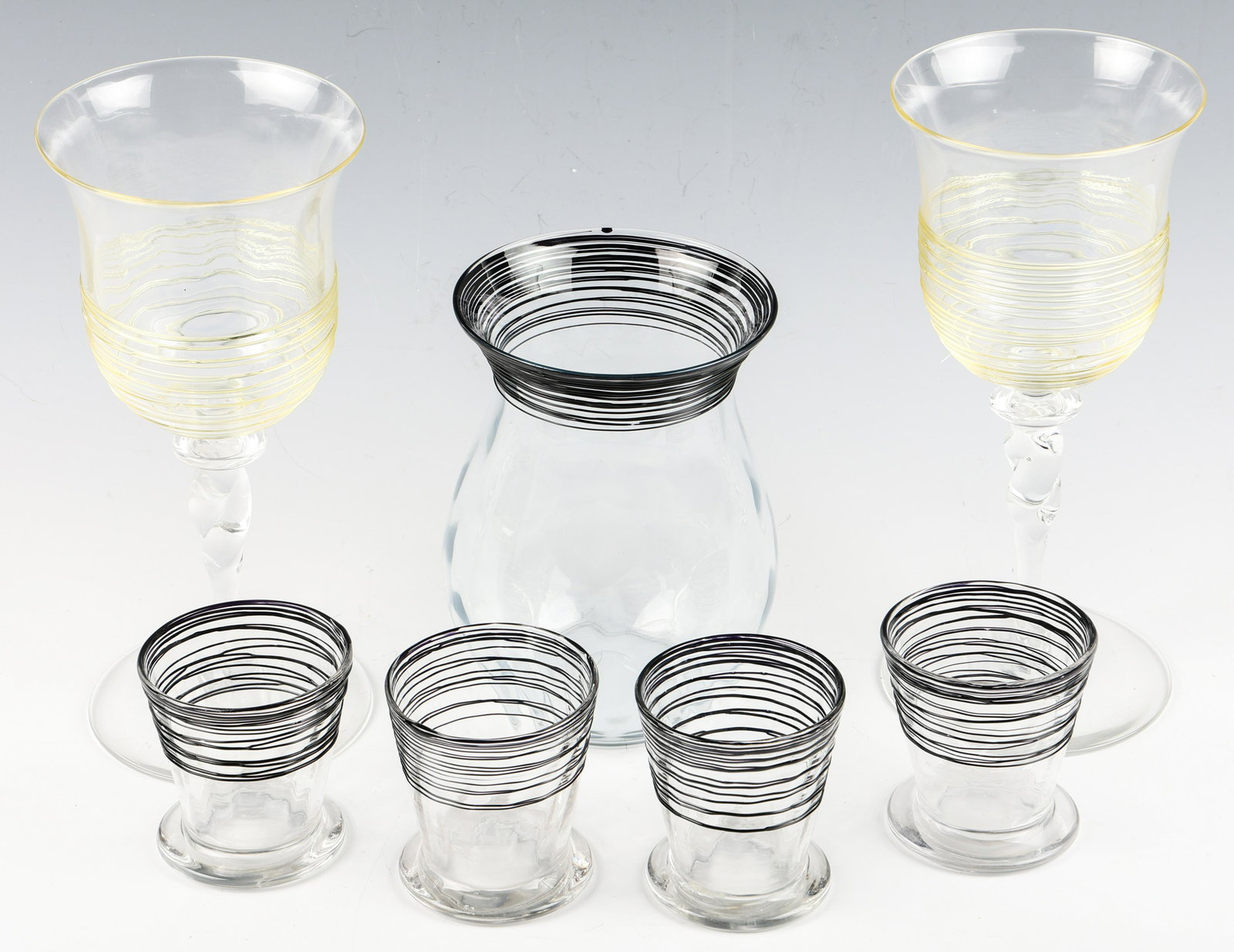STEUBEN GLASS CUPS, WINE GLASSES, & VASE: STEUBEN GLASS CUPS, WINE GLASSES, & VASE Lot of Steuben glass cups, wine glasses and a vase. Feature spun glass design accents. Marked to the underside of the base of the cups. Includes: 4 cups.