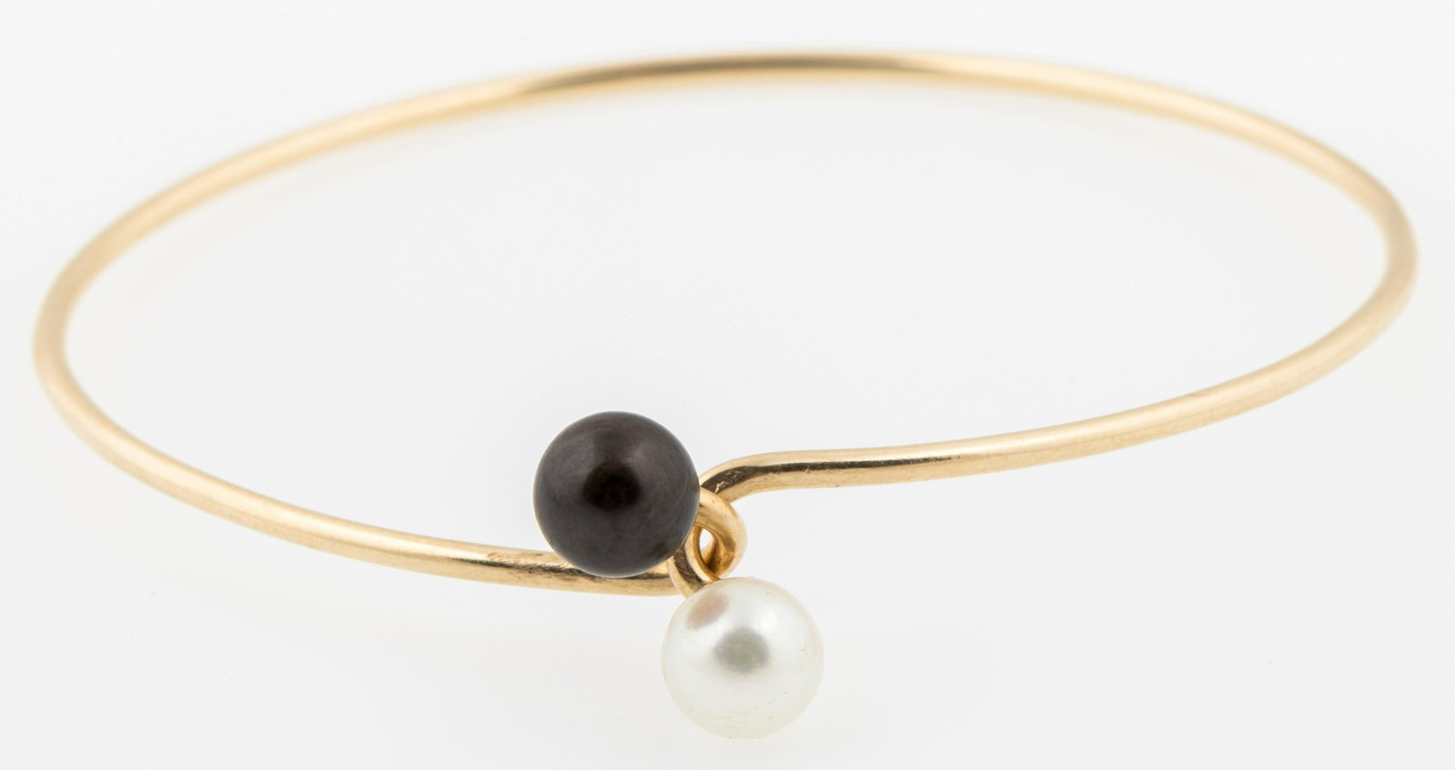 14K YELLOW GOLD TWIN PEARL BRACELET: 14K YELLOW GOLD TWIN PEARL BRACELET 14K yellow gold minimalist bracelet with a pair of black and white pearls. Approximately 6.5mm. Marked near hooking clasp. Size: Fits 6.5" Weight: 5.6 grams