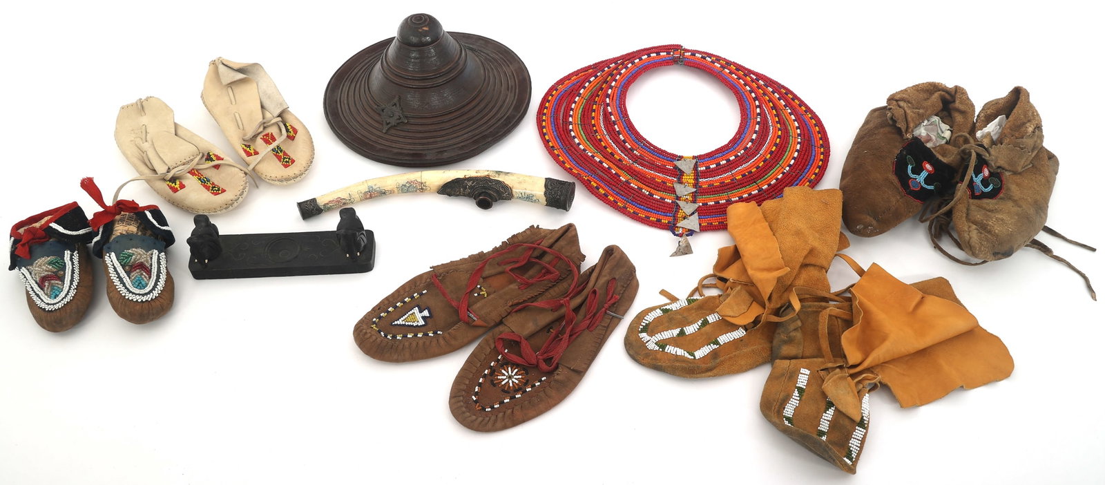ETHNOGRAPHIC TOURIST TRADE SOUVENIRS: ETHNOGRAPHIC TOURIST TRADE SOUVENIRS Ethnographic tourist trade souviners. Includes: (5) Pairs of leather moccasins in various sizes Massai glass beaded necklace 15" Zanzibar-Omani Hide Shield