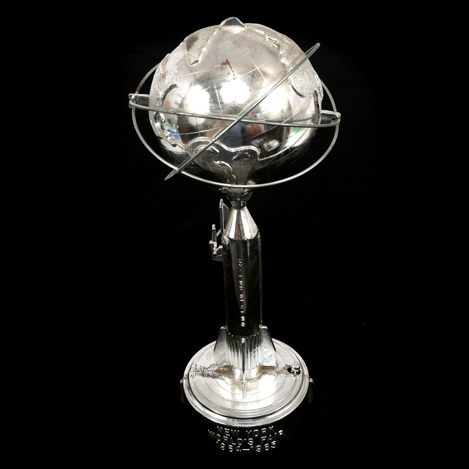 NEW YORK WORLD'S FAIR 1964 DIE-CAST MECHANICAL COIN BANK: NEW YORK WORLD'S FAIR 1964 DIE-CAST MECHANICAL COIN BANK 1964 New York World's Fair die-cast mechanical coin bank shaped like a rocket with the Unisphere. Size: 10.75 x 4"