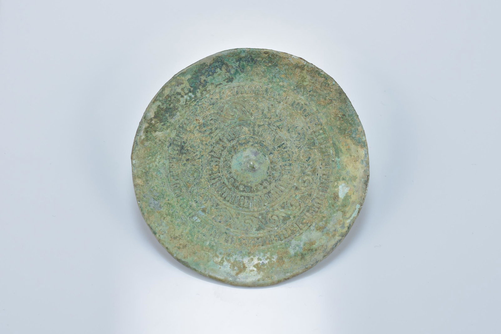 A Chinese Warring States / Han dynasty bronze circular: A Chinese Warring States / Han dynasty bronze circular attachment. Concave face with pattern design and the reverse with looped hook. 6cm diameter