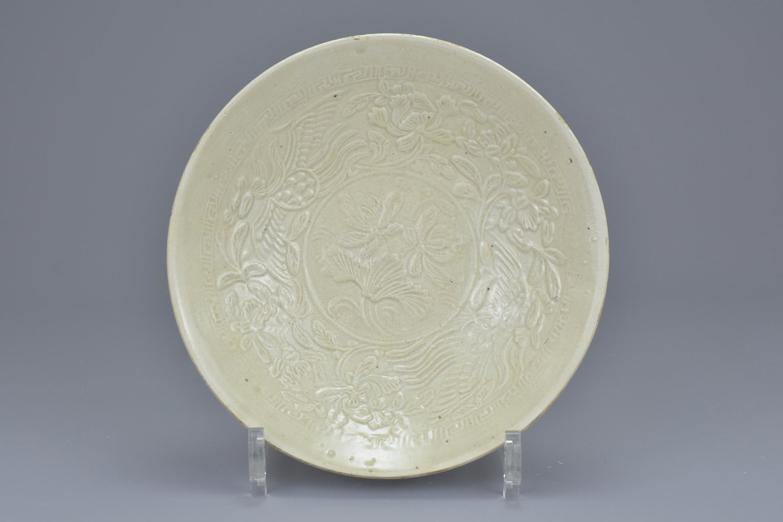 A Chinese Song dynasty (960-1279) Ding type bowl with: A Chinese Song dynasty (960-1279) Ding type bowl with peonies and phoenix design in relief.17.5cm diam. With original certificate of authenticity dated April 25th 1986 from Hong Kong Art Craft Merchan