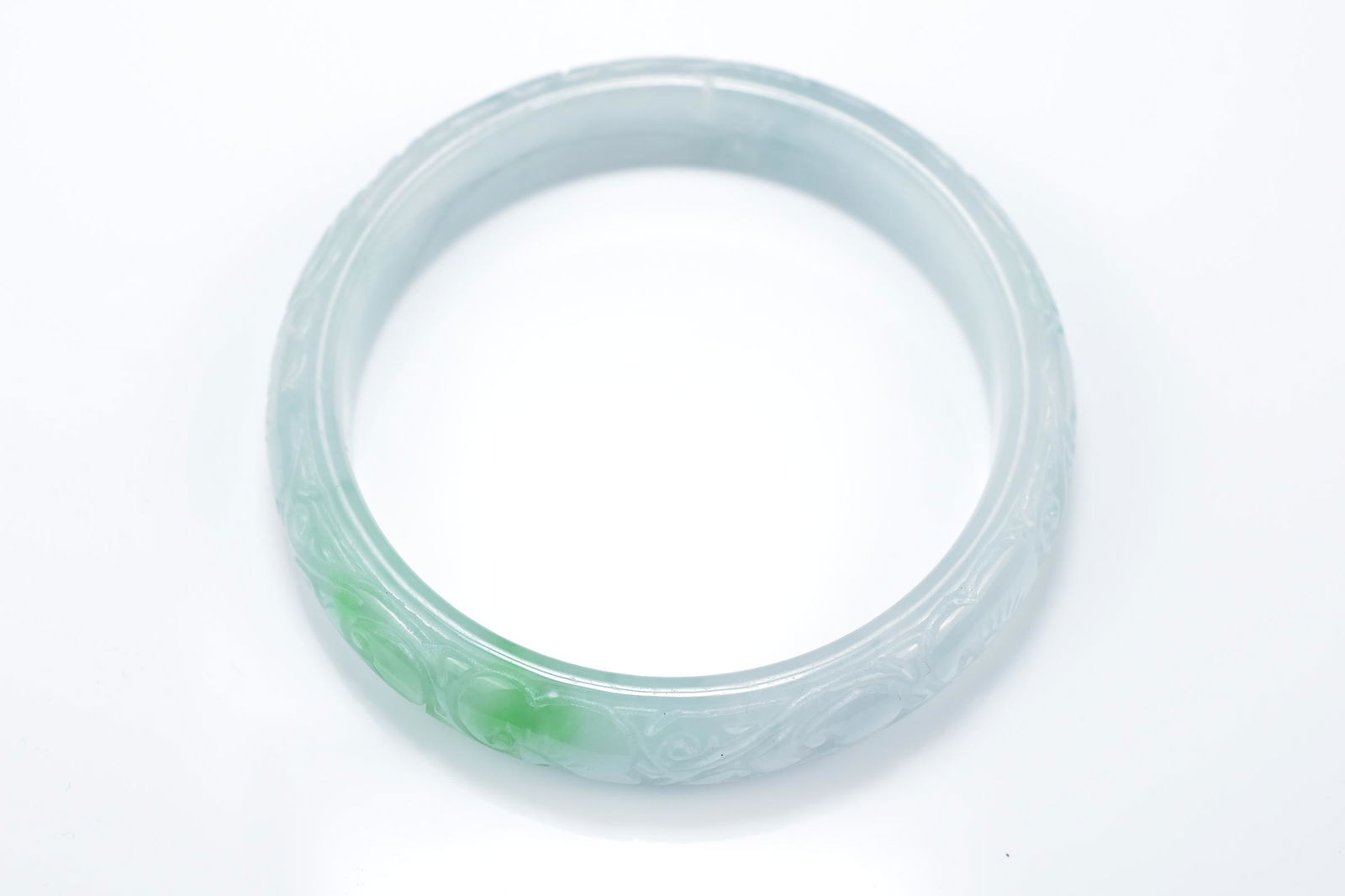 A Chinese carved jadeite bangle in pale white and green (1 of 4)