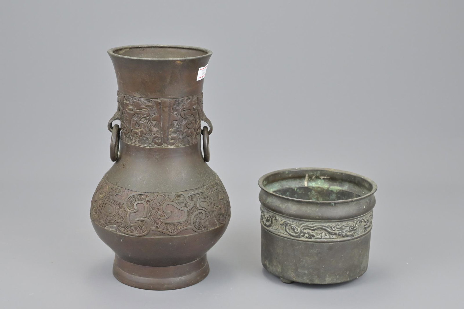 A chinese bronze censer with shallow tripod feet: A chinese bronze censer with shallow tripod feet together with a gu vase with twin looped handles and mythical beast decoration. vase height approx. 22cm (2)