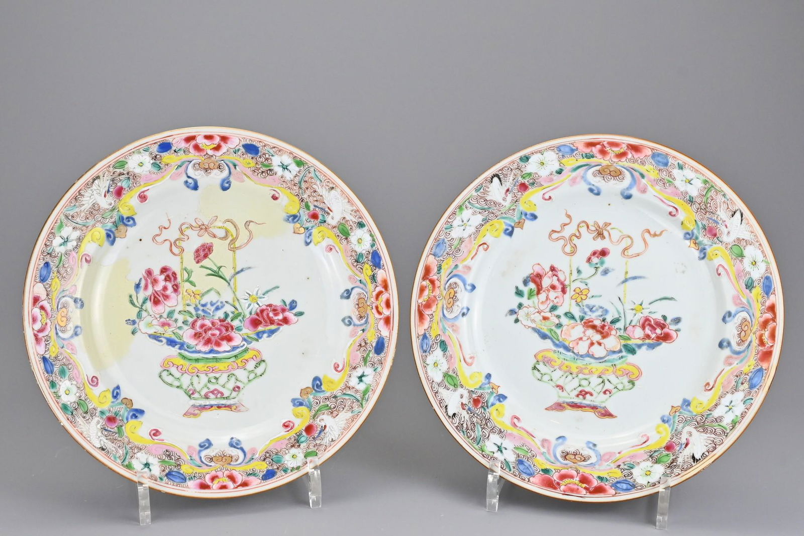A pair of Chinese 18th century famille rose porcelain: A pair of Chinese 18th century famille rose porcelain plates decorated with baskets of flowers. 22.5cm diam. (2)Both dishes with areas of porcelain repair with sections of overpaint.
