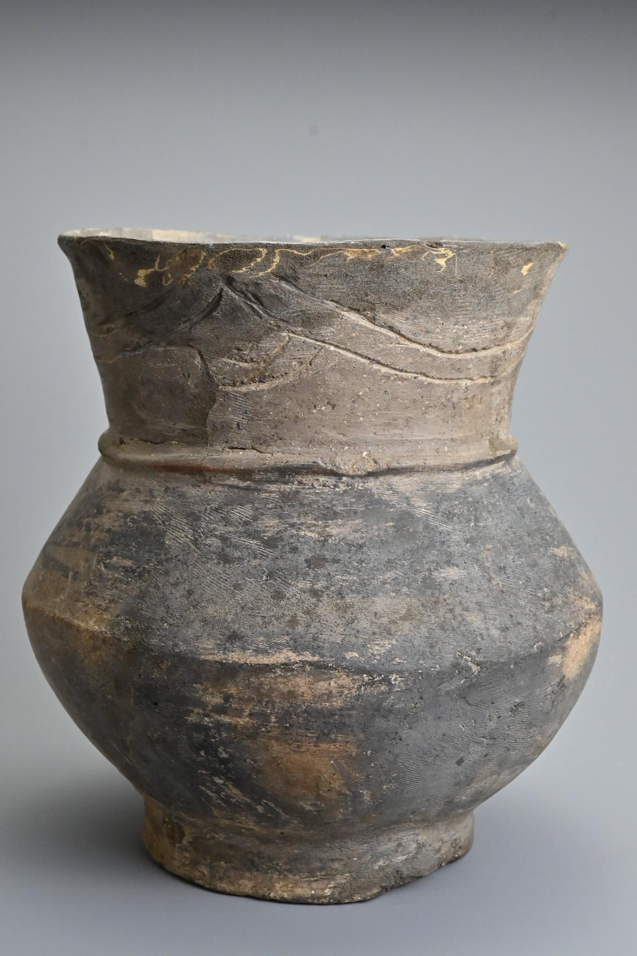 A Thai pottery jar. With globular squat body on shallow: A Thai pottery jar. With globular squat body on shallow foot with fluted rim with incised line decoration. Possibly Ban Chiang (300BC - 200AD). 20.5cm tall. From a private New York collection, acquire