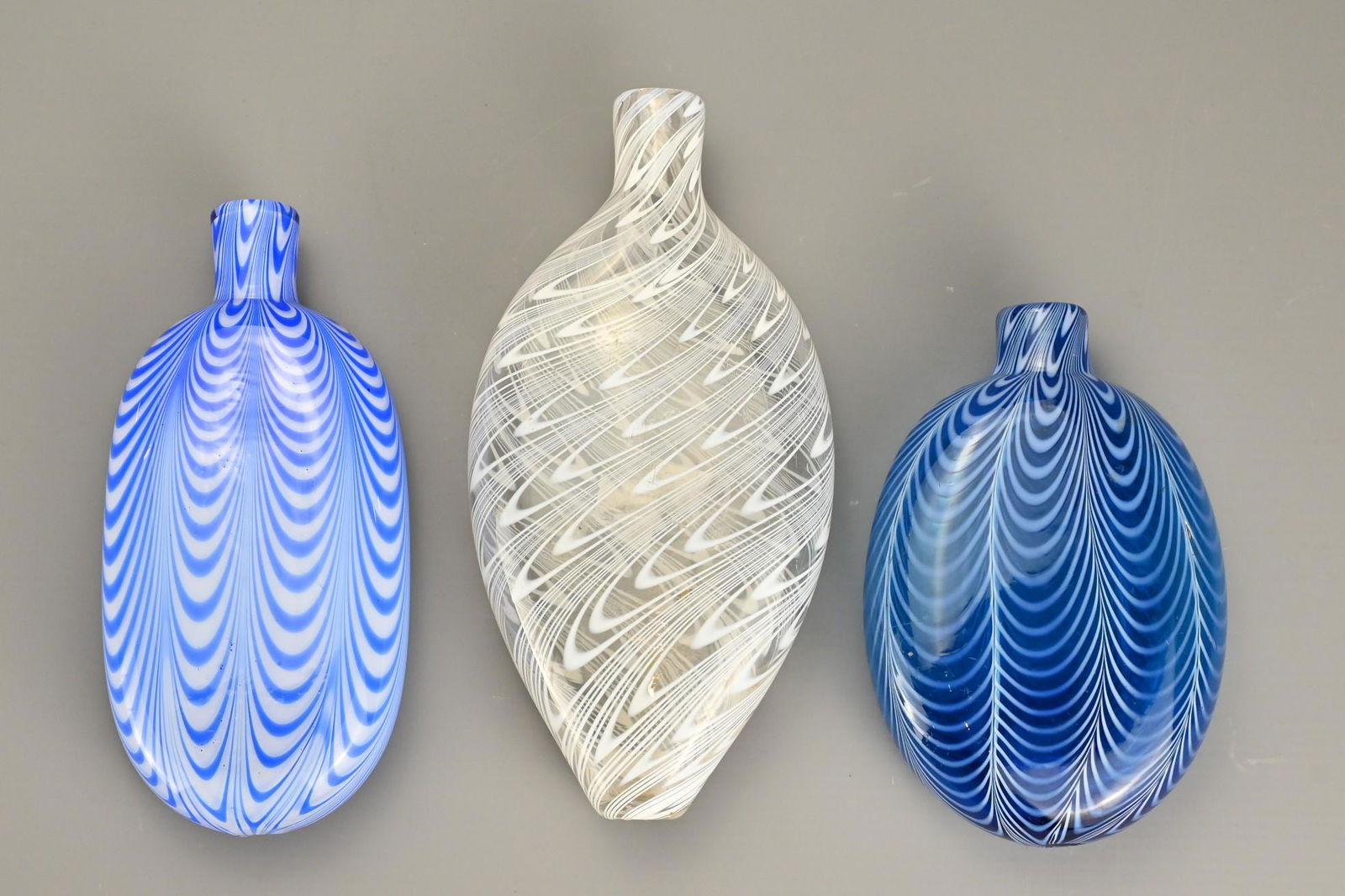 Three Bristol Nailsea Glass Flasks, 19th Century, one: Three Bristol Nailsea Glass Flasks, 19th Century, one in blue glass decorated with white trailing, clear glass with white diagonal trailing and one with blue and white trailing, largest 21 cm tall (3)