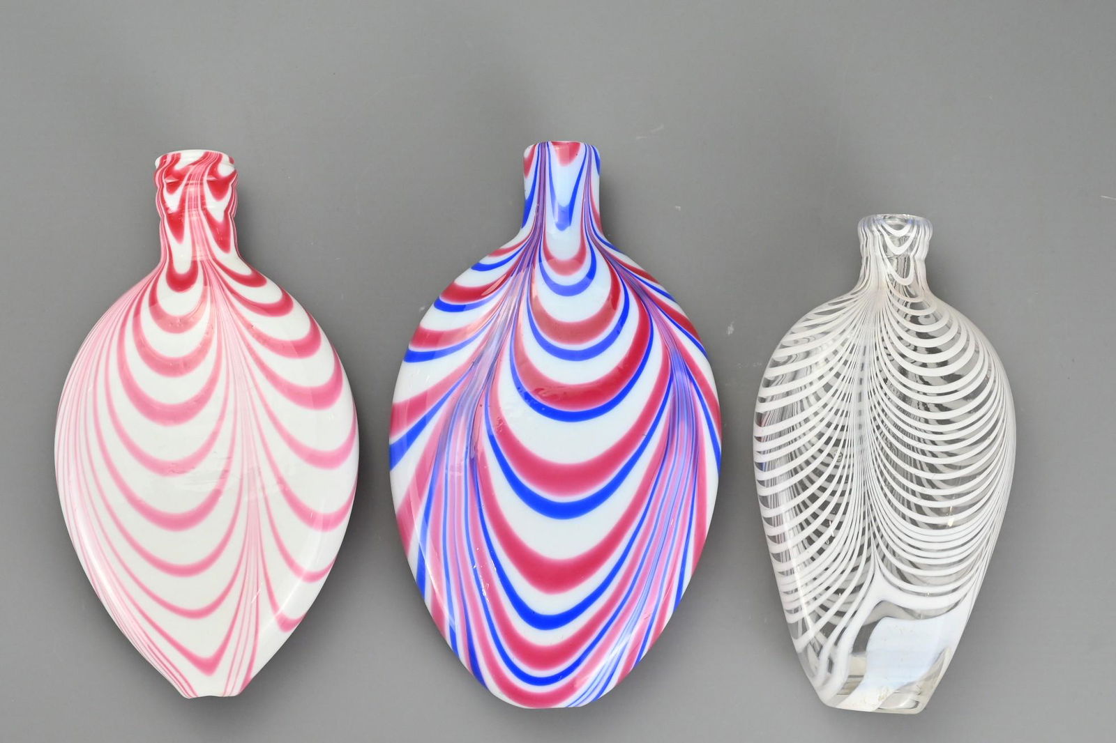 Three Bristol Nailsea Glass Flasks, 19th Century, one: Three Bristol Nailsea Glass Flasks, 19th Century, one clear glass decorated with white trailing, one white glass with pink trailing and one white glass with blue and pink trailing, largest 21.5 cm tal