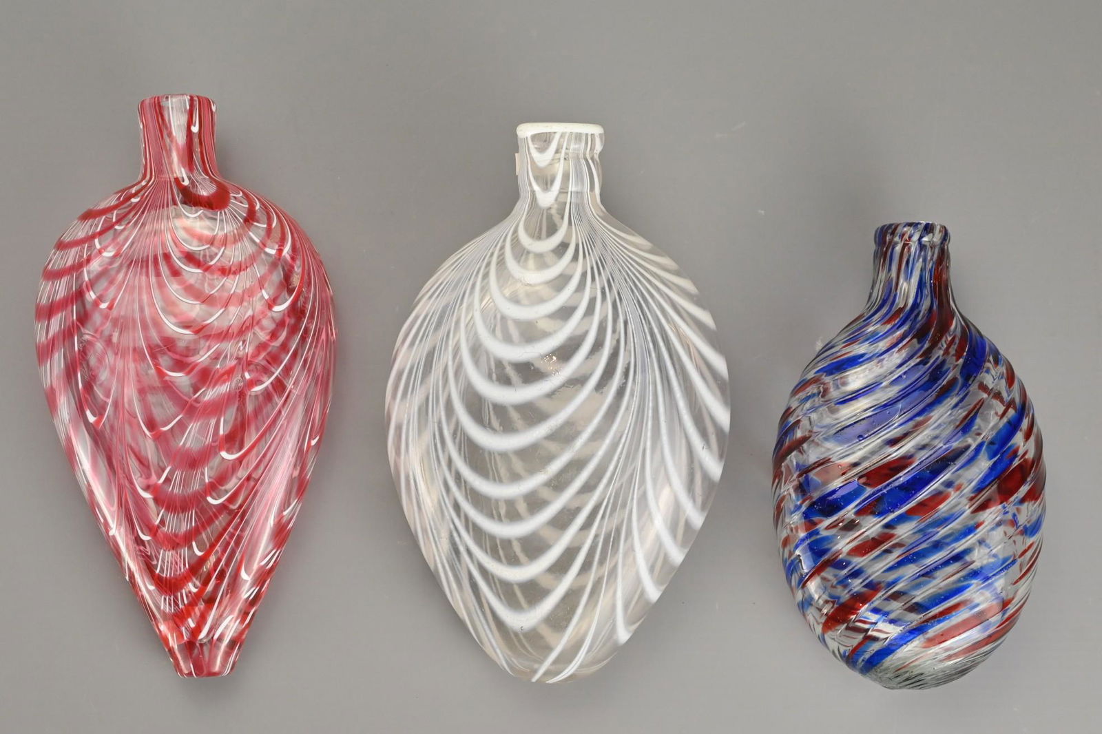 Three Bristol Nailsea Glass Flasks, 19th Century, one: Three Bristol Nailsea Glass Flasks, 19th Century, one clear glass decorated with white trailing, one clear glass with overlapping pink and white trailing and one clear twisted glass with blue and red