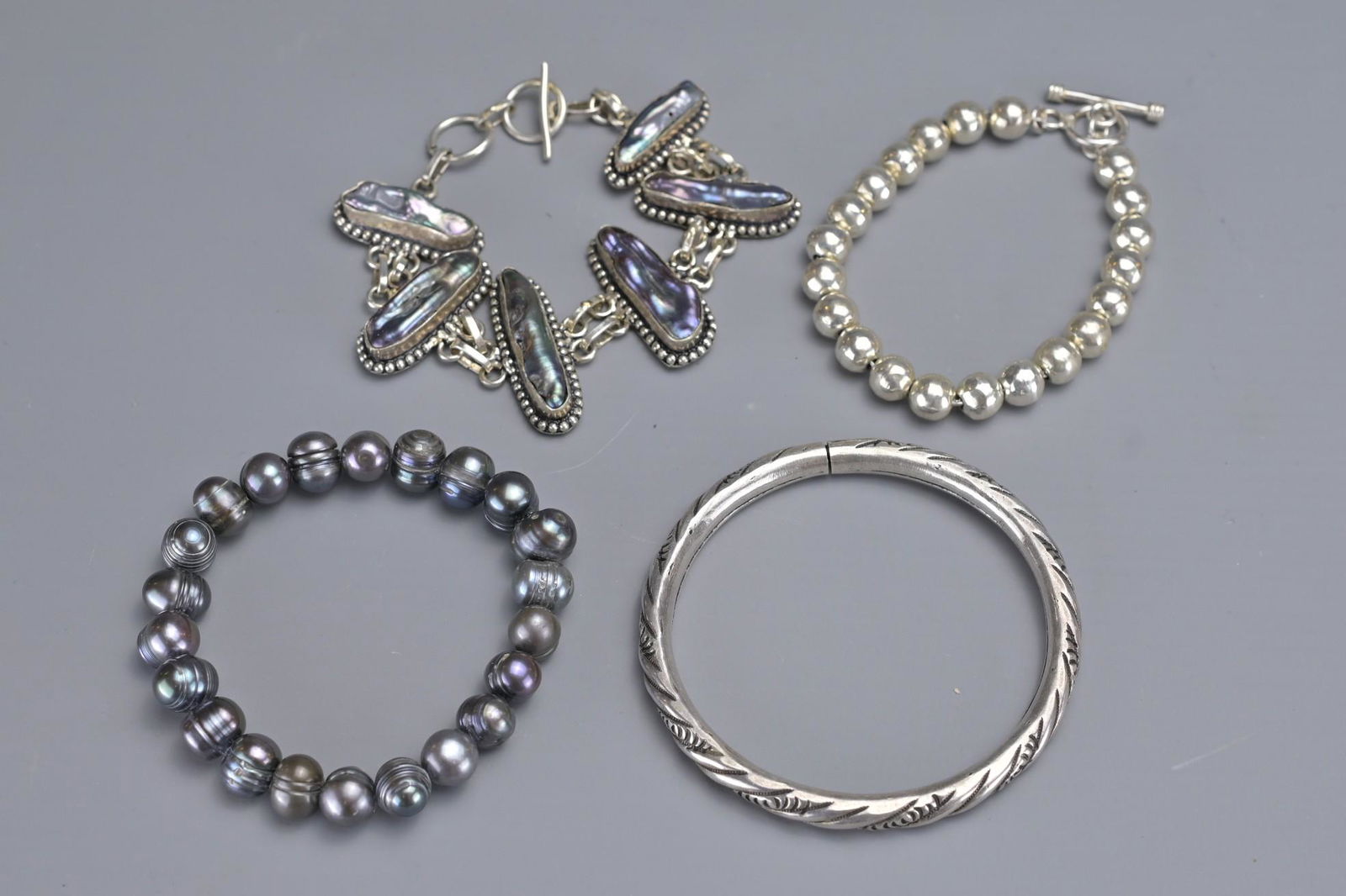 A GROUP OF FOUR SILVER AND PEARL BRACELETS AND BANGLE (1 of 6)