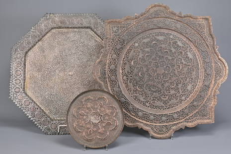 TWO COPPER INDO-PERSIAN TRAY-TABLE TOPS AND A SMALL DISH SIMILAR, EARLY 20TH CENTURY. The first: TWO COPPER INDO-PERSIAN TRAY-TABLE TOPS AND A SMALL DISH SIMILAR, EARLY 20TH CENTURY. The first tinned/silvered and of octagonal section, pierced with shaped flowerheads to the border the centre dense