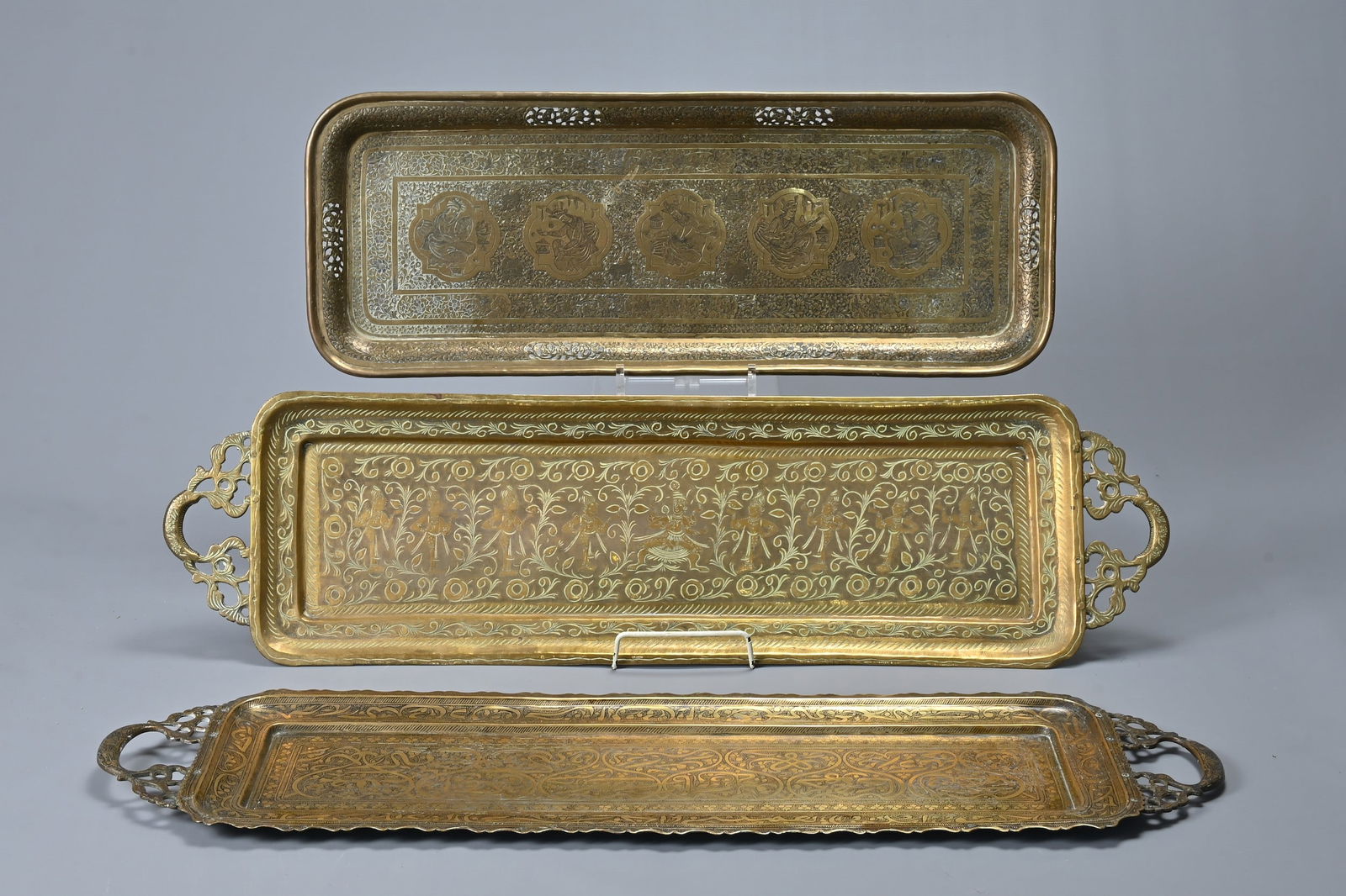 THREE MIDDLE EASTERN BRASS RECTANGULAR TRAYS, 20TH CENTURY. The first decorated with figures (1 of 6)