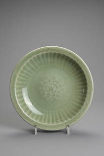 A CHINESE LONGQUAN CELADON PORCELAIN FOLIATE DISH, MING DYNASTY OR LATER. Decorated with a central: A CHINESE LONGQUAN CELADON PORCELAIN FOLIATE DISH, MING DYNASTY OR LATER. Decorated with a central peony medallion within a fluted well and band of lappets to the exterior, covered in an glassy olive